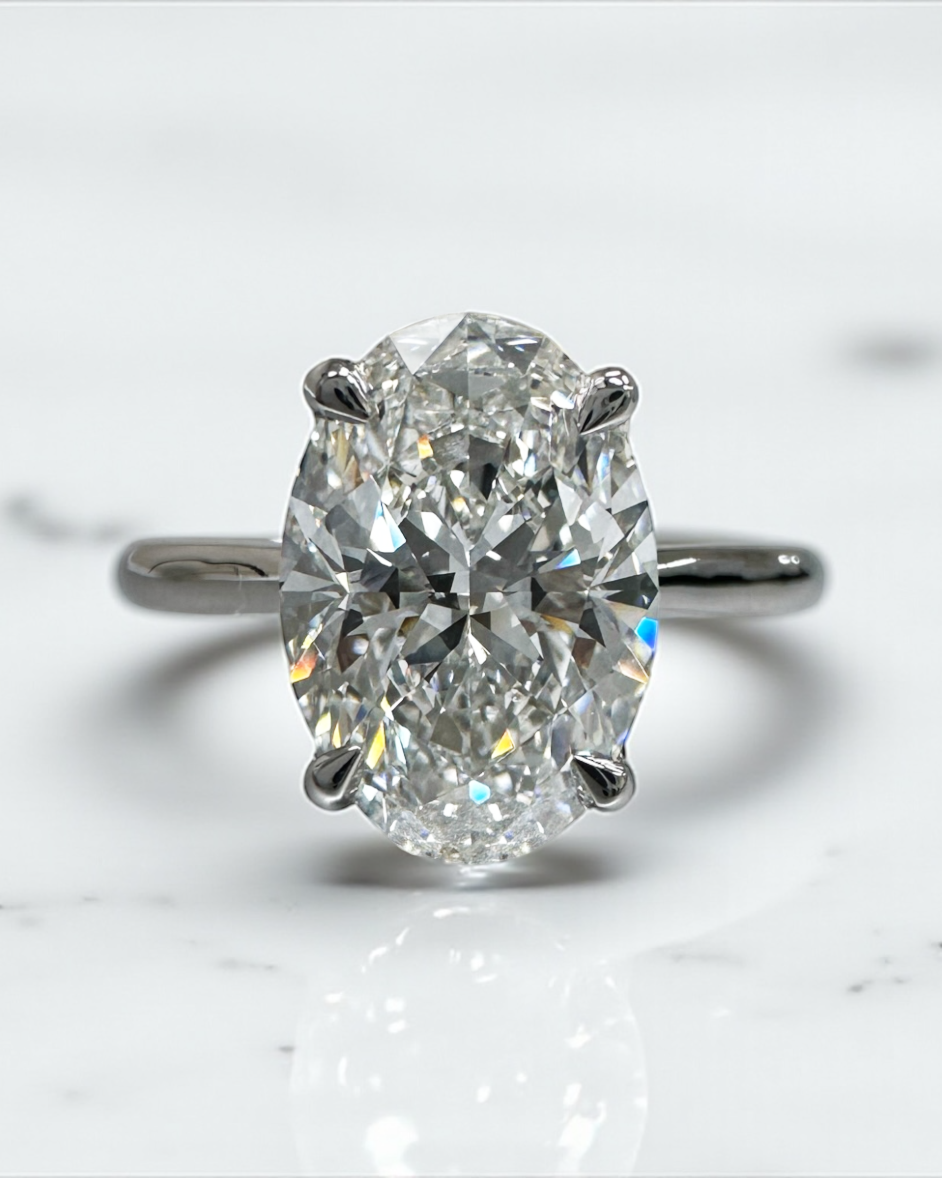 Close up of 3ct oval diamond solitaire ring in platinum cathedral setting with diamond bridge detail — Layla Diamonds London.