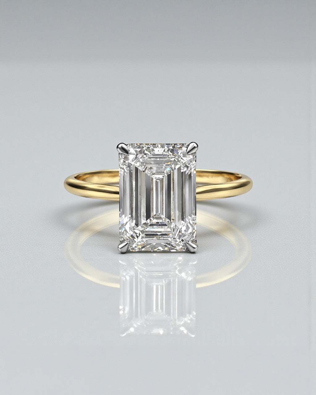 4ct emerald cut lab grown diamond engagement ring with hidden halo and diamond bridge in a cathedral setting 18kt yellow gold