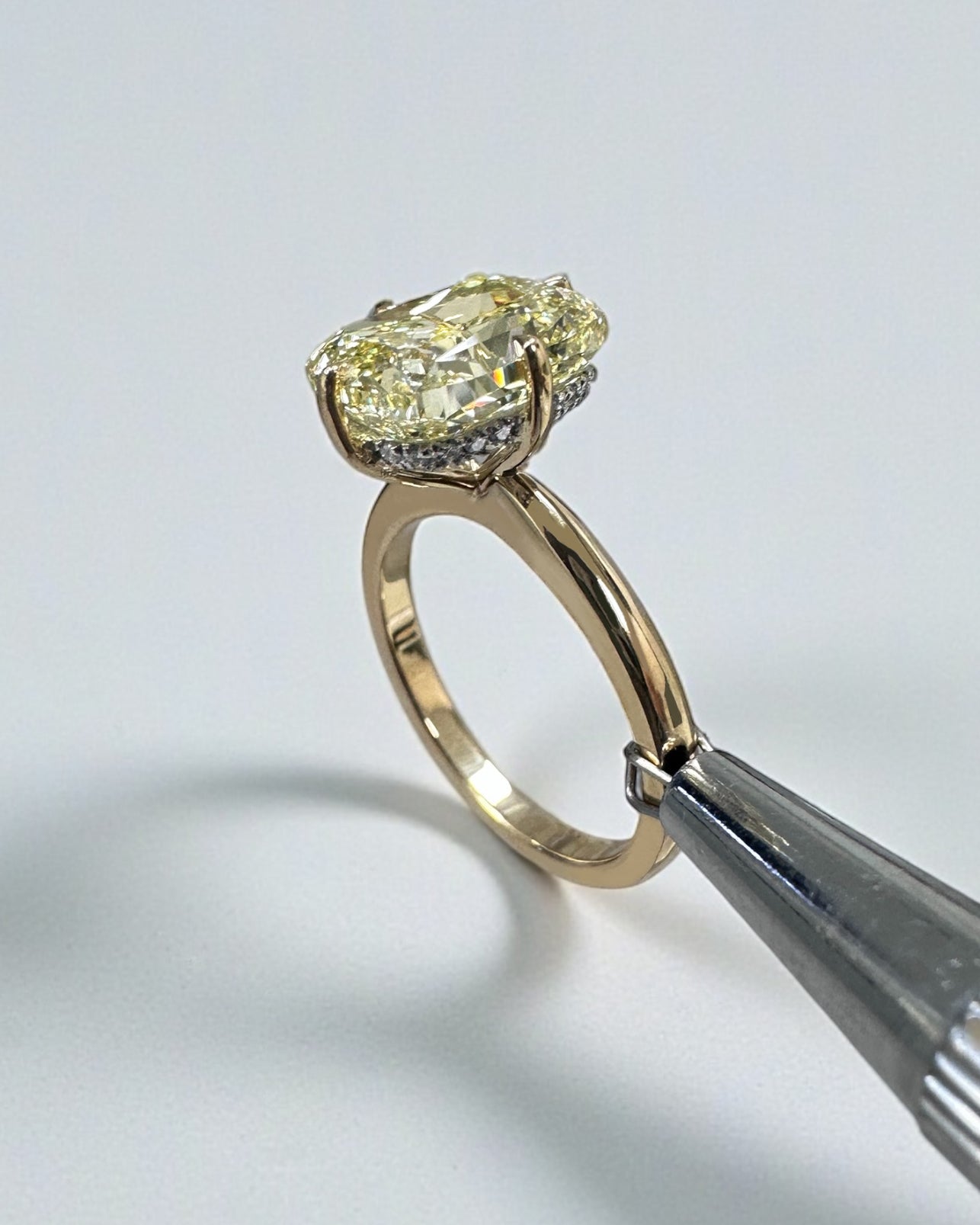 A stunning 5ct Fancy Intense Yellow elongated cushion cut diamond solitaire with platinum hidden halo and 18kt yellow gold band engagement ring. Bold, elegant and handcrafted in London.