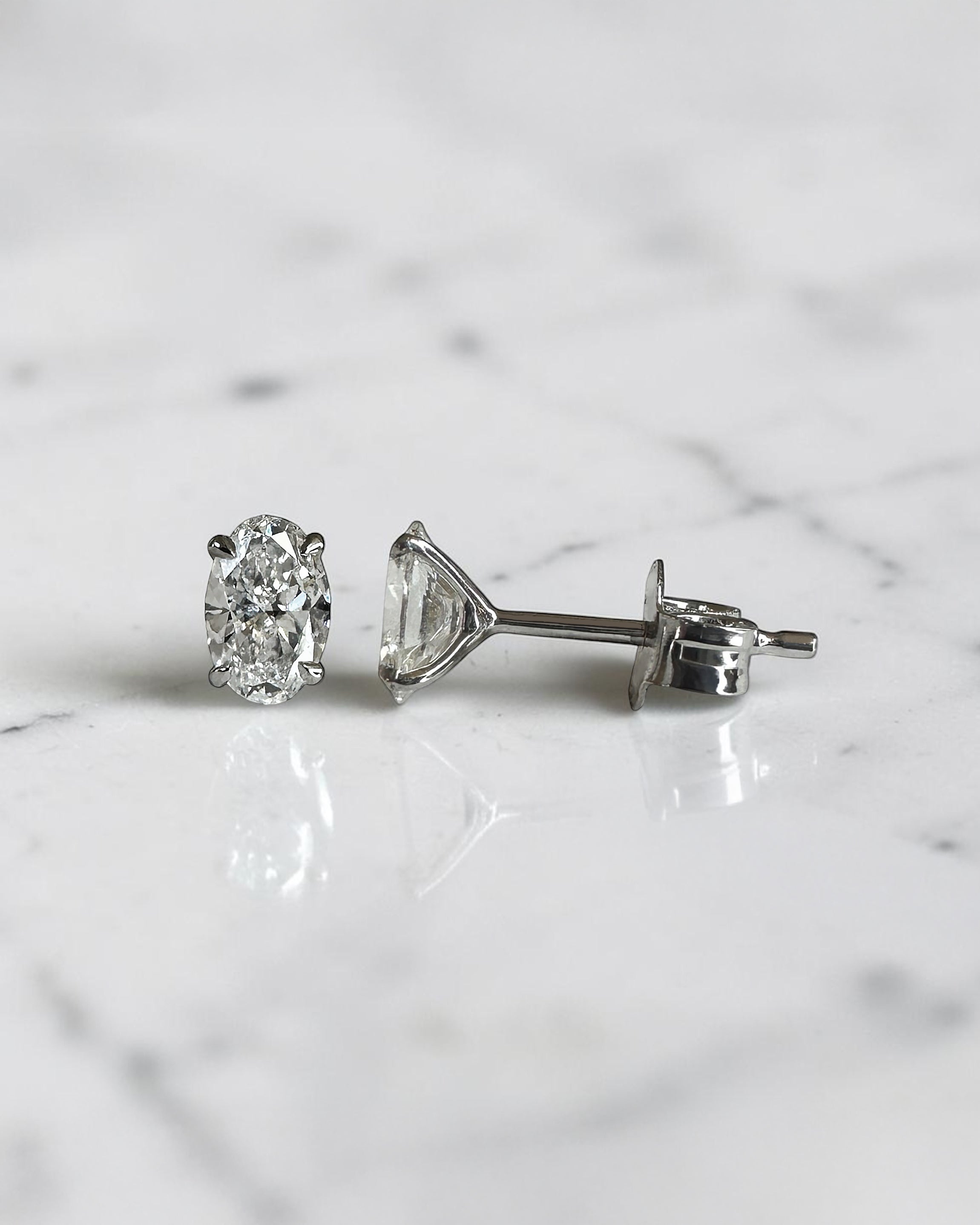 0.70ct oval diamond stud earrings featuring two 0.35ct oval brilliant cut diamonds in a classic four prong setting with secure butterfly backs.