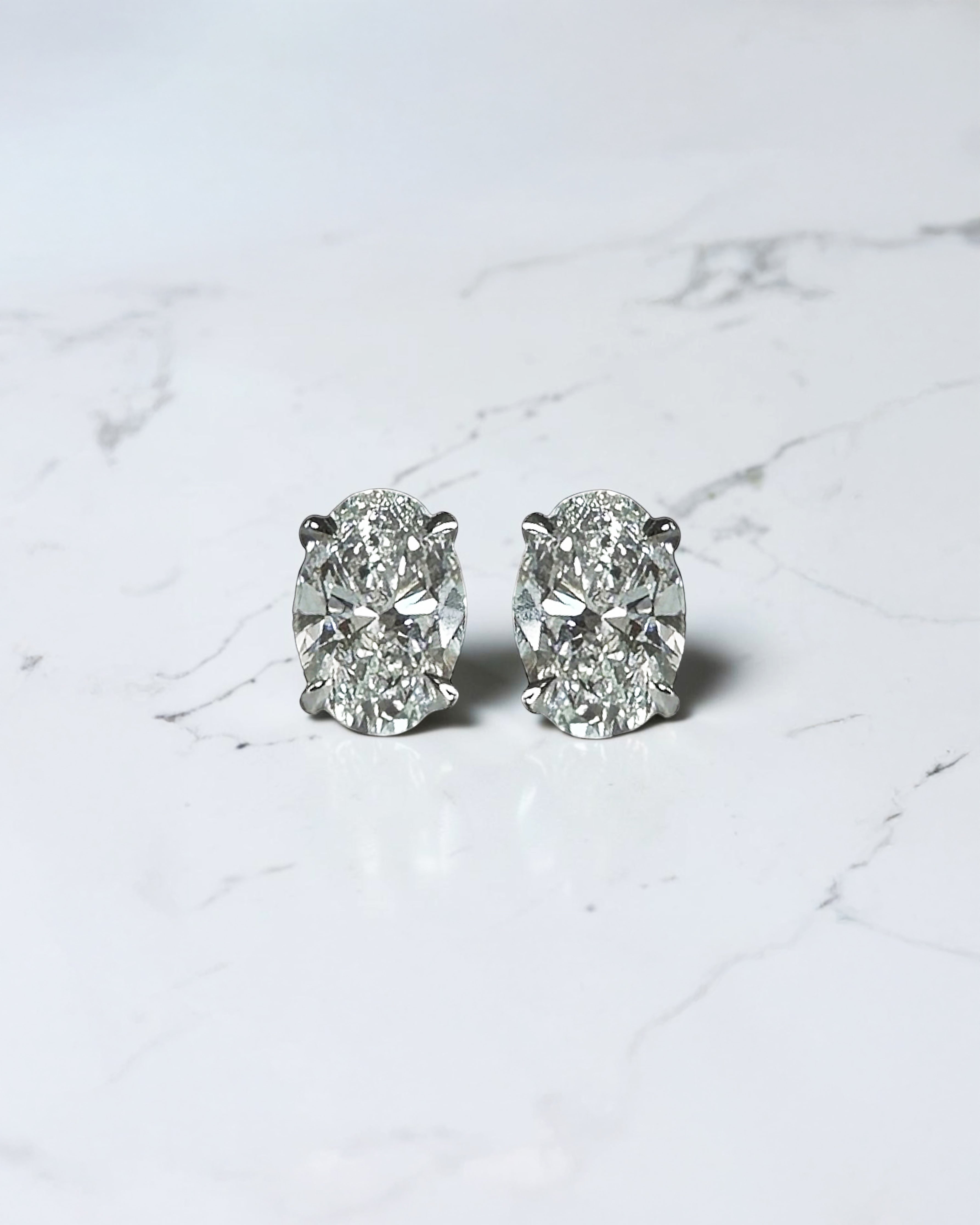 0.70ct oval diamond stud earrings featuring two 0.35ct oval brilliant cut diamonds in a classic four prong setting with secure butterfly backs.