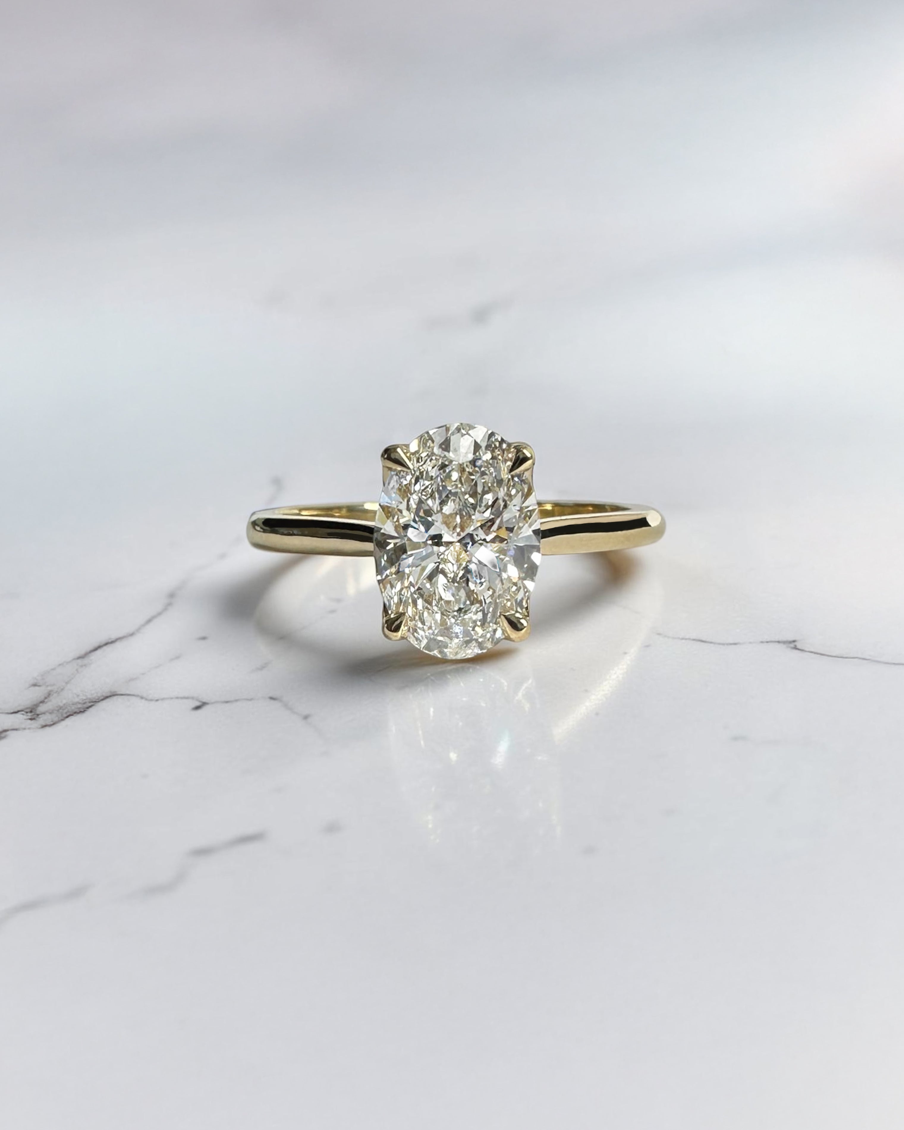 Close up of oval diamond engagement ring with hidden pavé bridge and cathedral setting