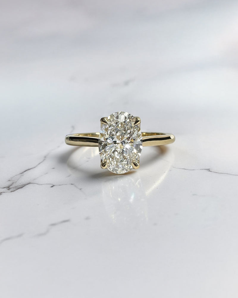 Close up of oval diamond engagement ring with hidden pavé bridge and cathedral setting