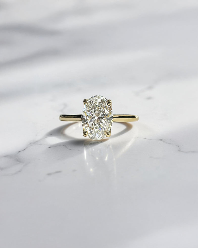 Oval cut diamond cathedral engagement ring with hidden diamond bridge in 18kt yellow gold, approx 1.60ct total