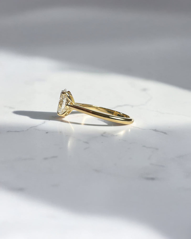 Side view of oval diamond cathedral ring showing hidden diamond bridge detail in 18kt yellow gold