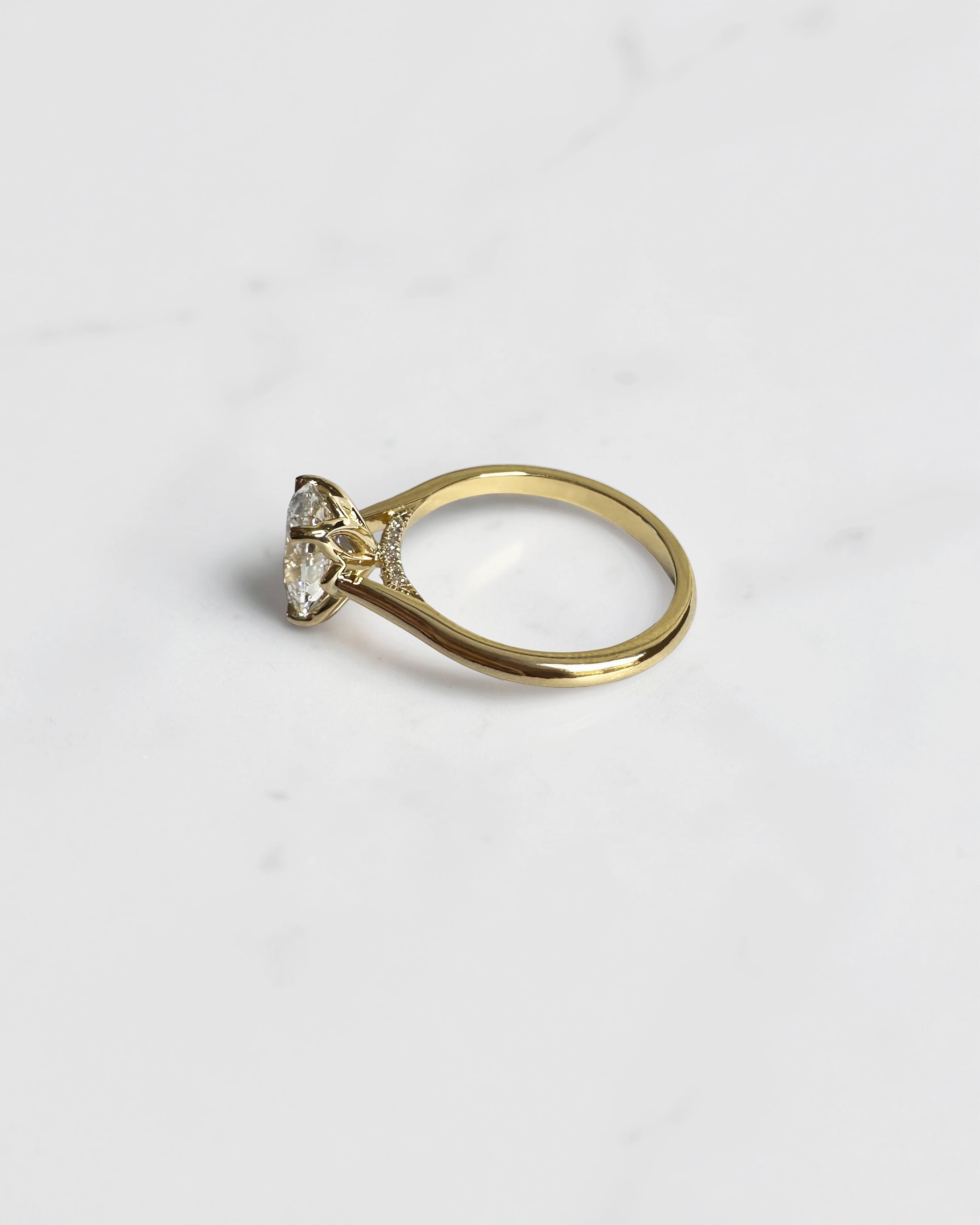 Close up of oval diamond engagement ring with hidden pavé bridge and cathedral setting