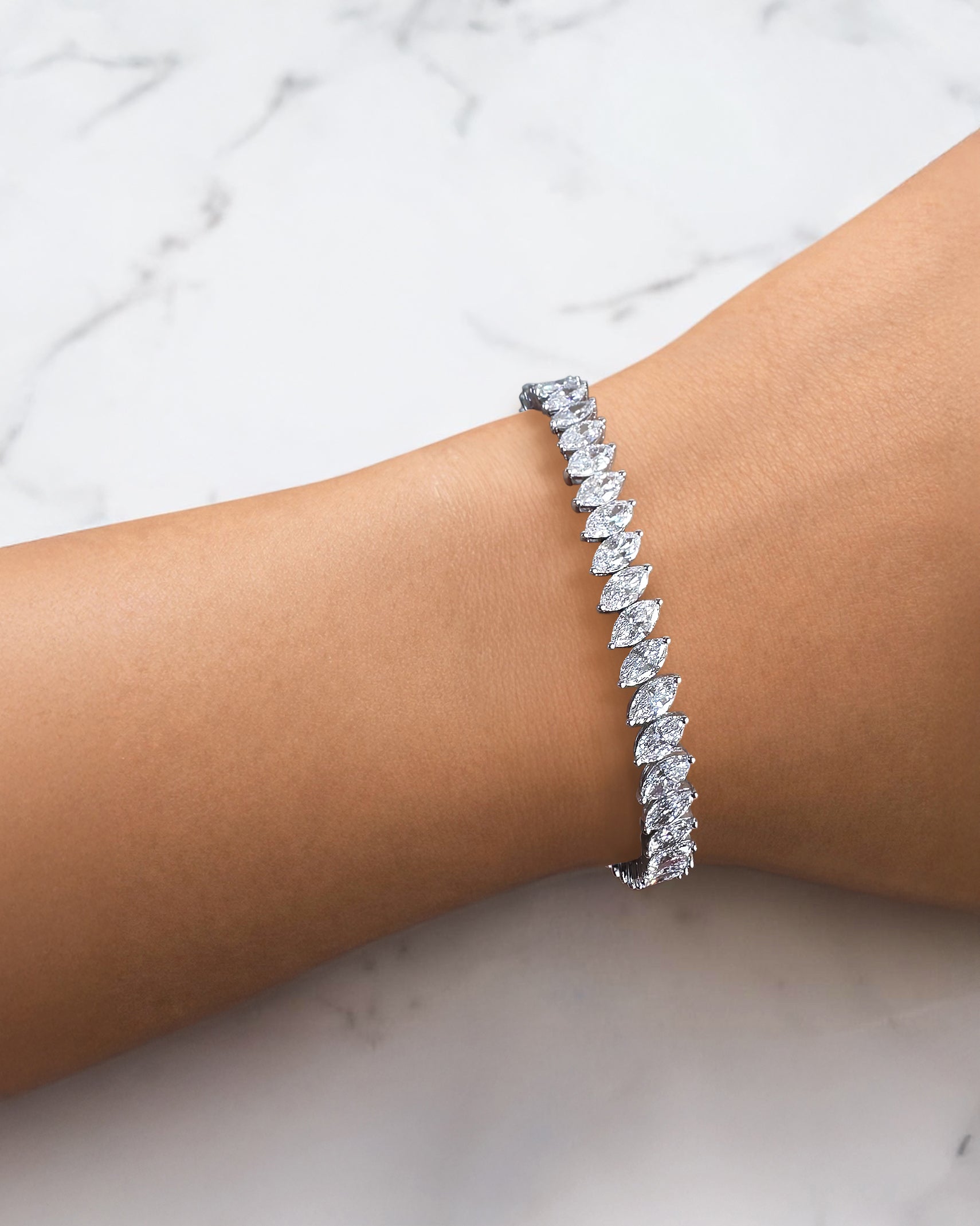 12ct slanted marquise cut diamond tennis bracelet on wrist in white gold featuring sparkling marquise diamonds in a modern slanted setting.