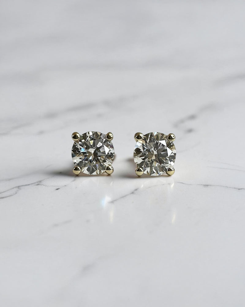 1ct round brilliant lab grown diamond stud earrings in a 4 prong martini setting with 0.50ct E/F VS1+ diamonds in yellow gold.