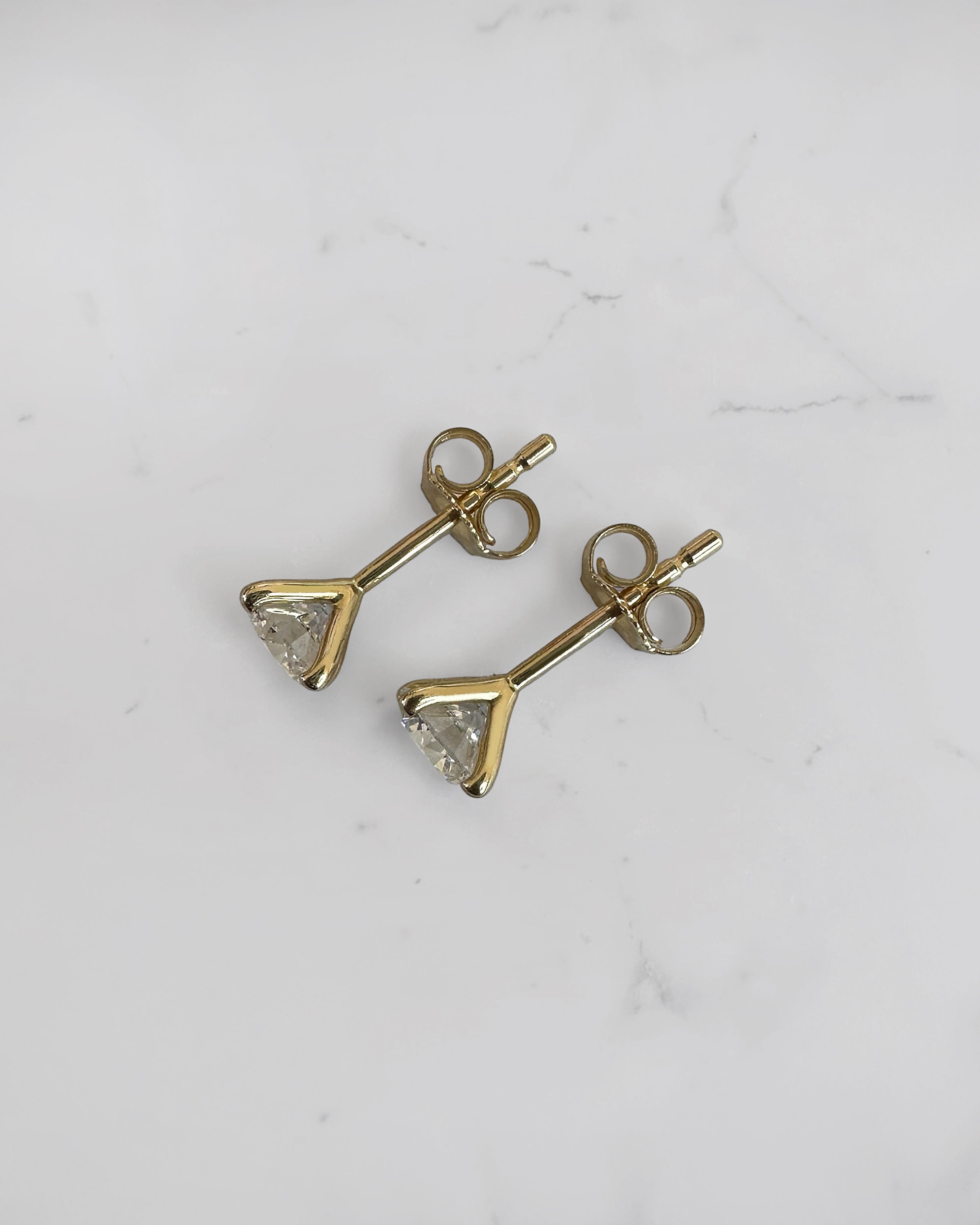 1ct round brilliant lab grown diamond stud earrings in a 4 prong martini setting with 0.50ct E/F VS1+ diamonds in yellow gold.