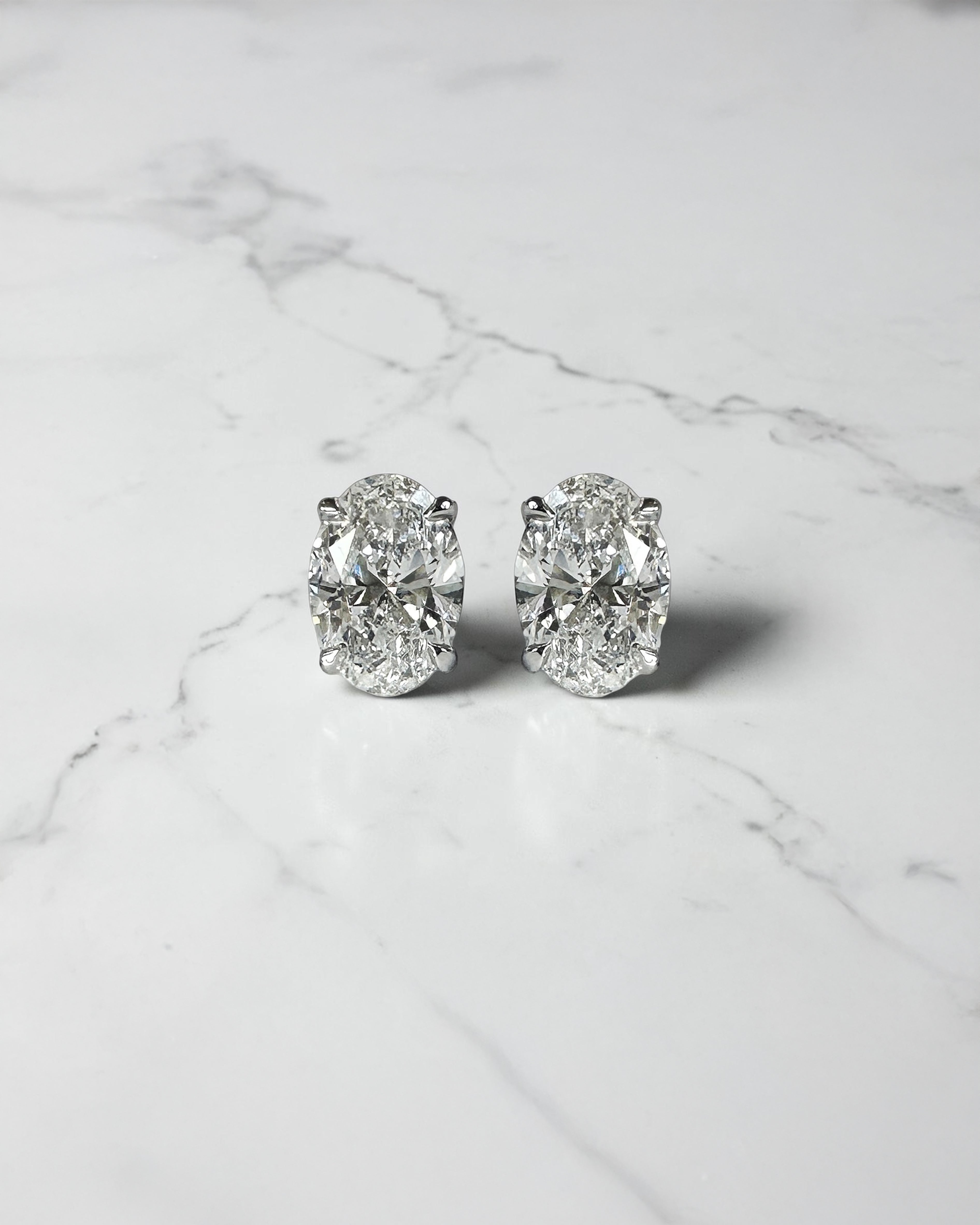 1ct oval diamond stud earrings featuring two 0.50ct oval brilliant cut diamonds in a classic four prong setting, available in platinum or gold.