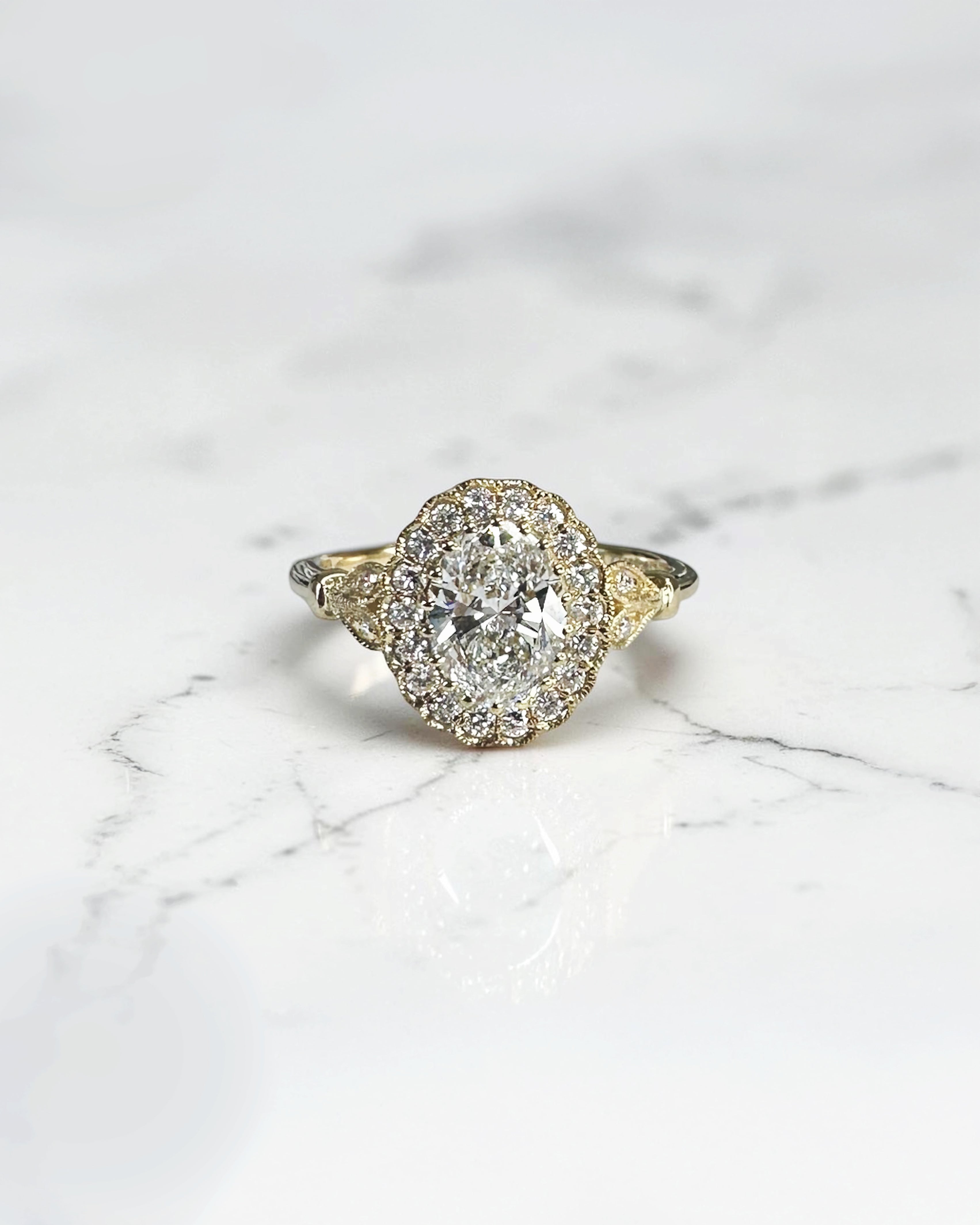 1ct oval vintage style halo diamond engagement ring in yellow gold with diamond halo, vintage shoulders and intricate gallery detail.