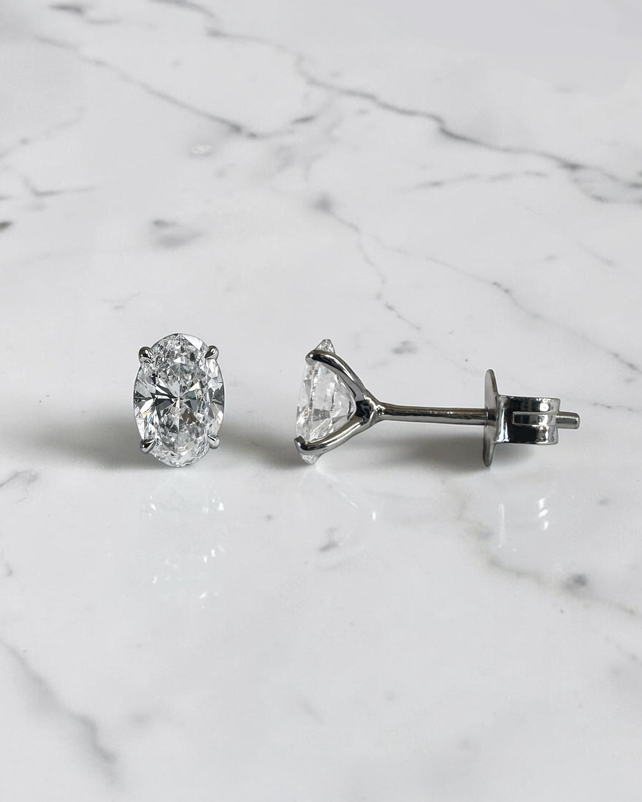 1ct oval diamond stud earrings featuring two 0.50ct oval brilliant cut diamonds in a classic four prong setting, available in platinum or gold.