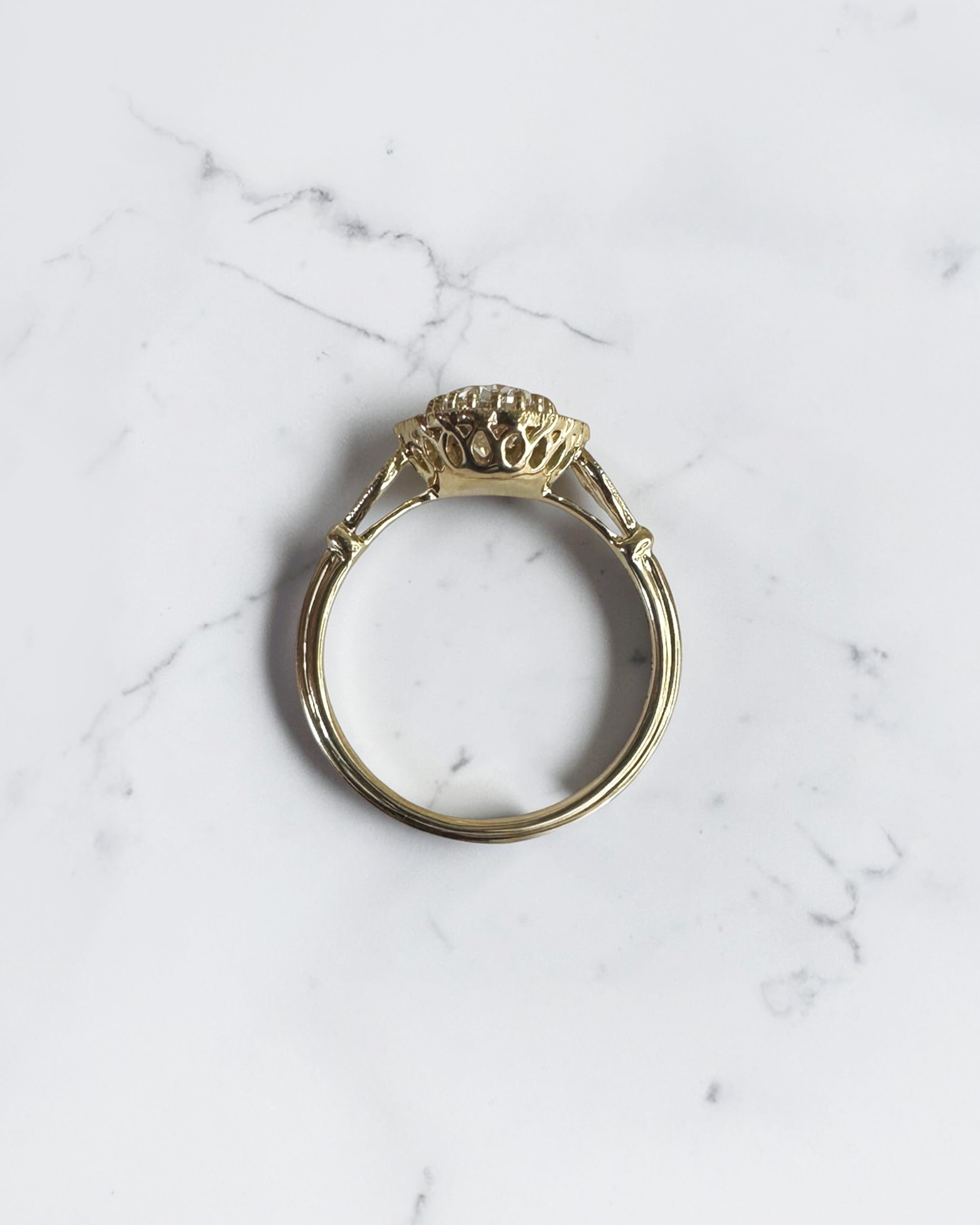 1ct oval vintage style halo diamond engagement ring in yellow gold with diamond halo, vintage shoulders and intricate gallery detail.