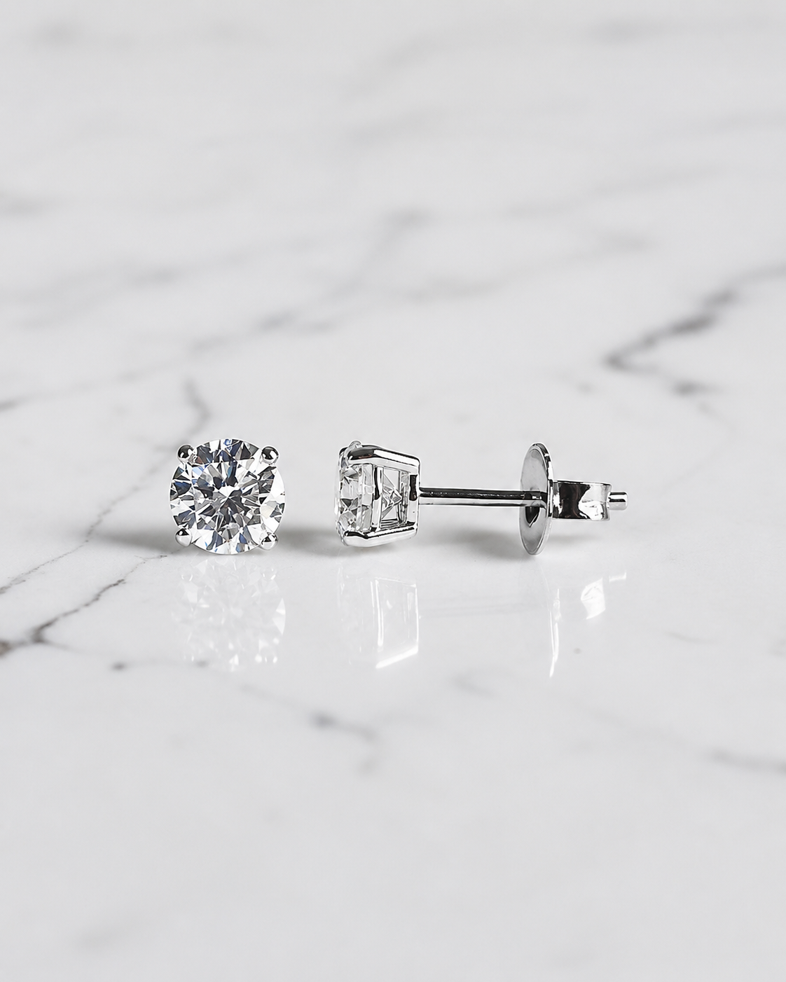 1ct round brilliant lab grown diamond stud earrings with 0.50ct diamonds in a classic four claw basket setting, available in white gold, yellow gold or platinum.