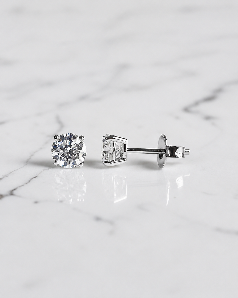 1ct round brilliant lab grown diamond stud earrings with 0.50ct diamonds in a classic four claw basket setting, available in white gold, yellow gold or platinum.