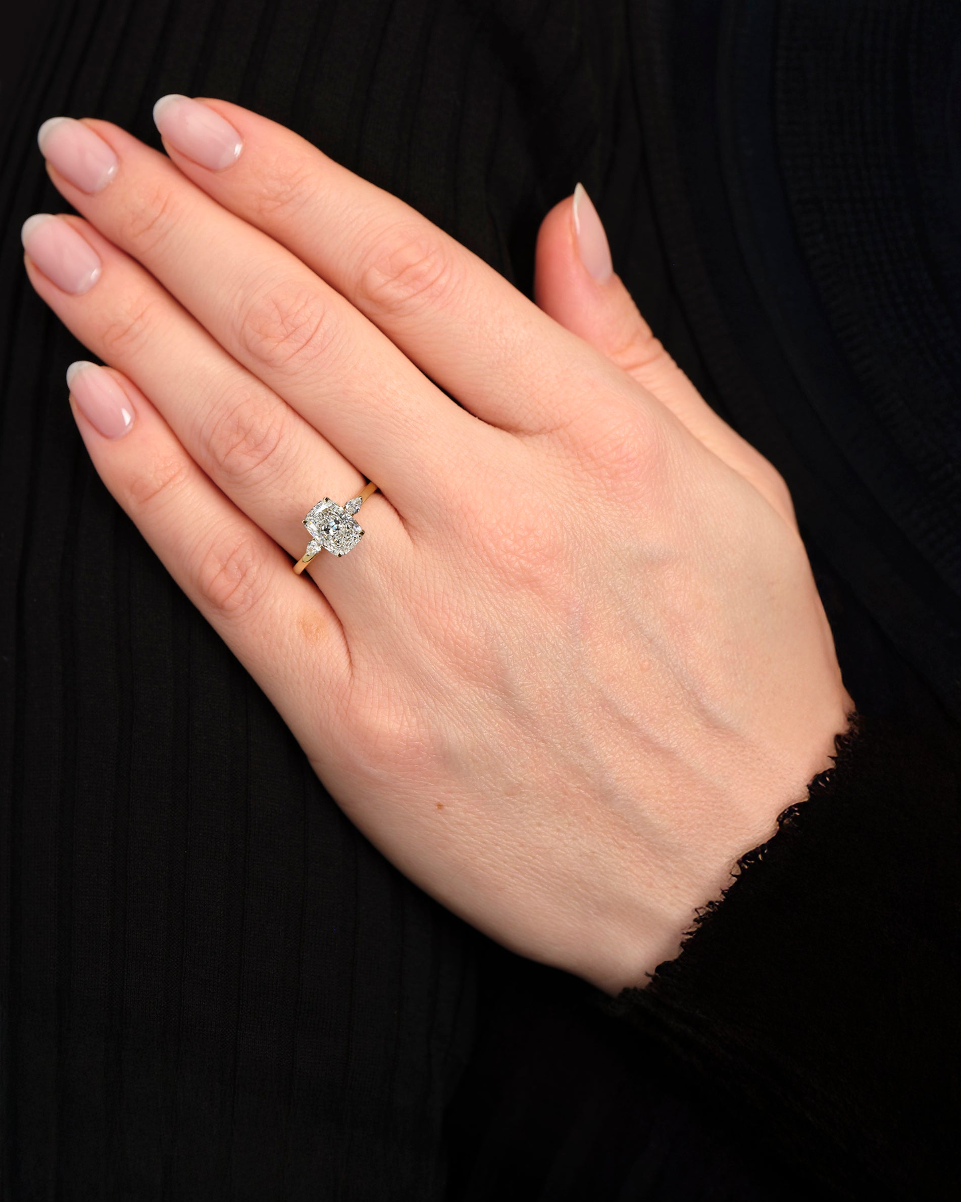 elongated cushion cut diamond trilogy ring 2ct centre with pear diamond side stones 18kt yellow gold engagement ring on hand