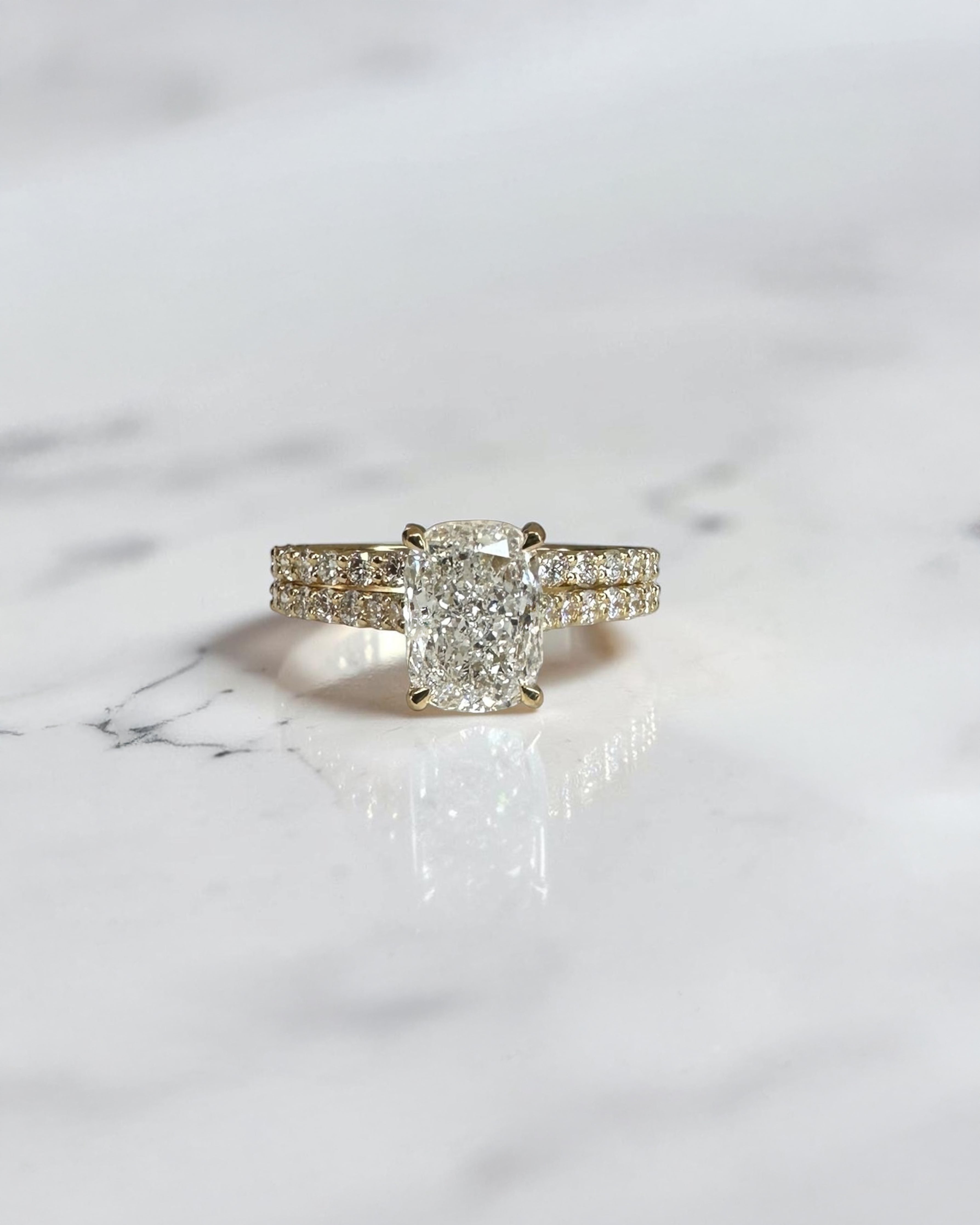 2ct elongated cushion cut lab grown diamond engagement ring paired with diamond wedding band in yellow gold