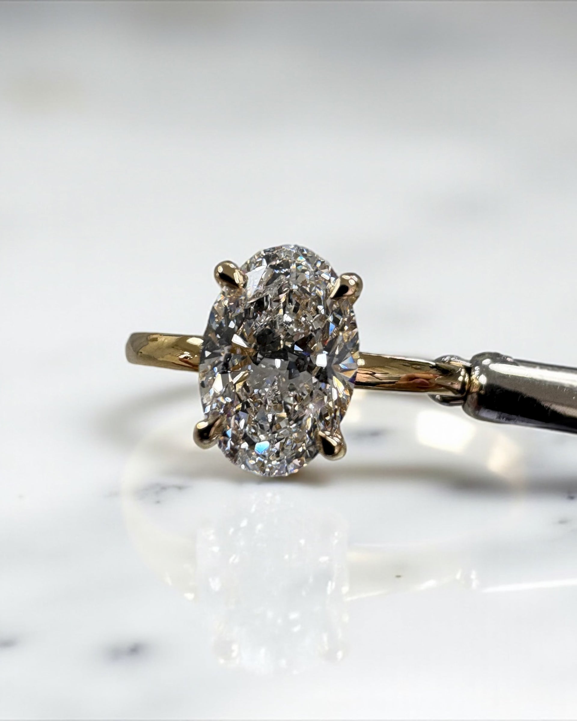 2ct oval cut lab grown diamond floating head engagement ring with hidden halo on a plain soft court band in 18kt yellow gold 