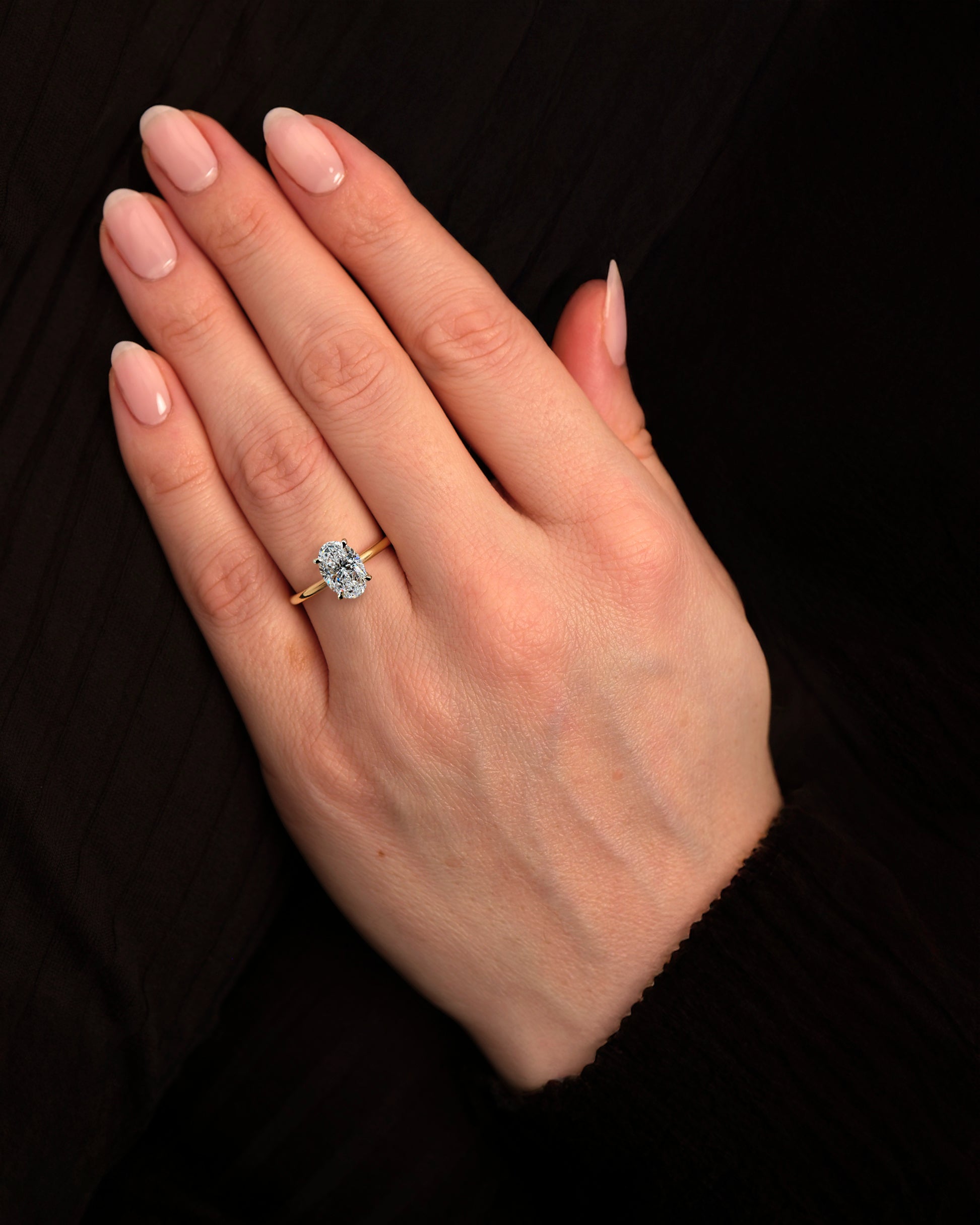 2ct oval cut lab grown diamond floating head engagement ring with hidden halo on a plain soft court band in 18kt yellow gold on hand