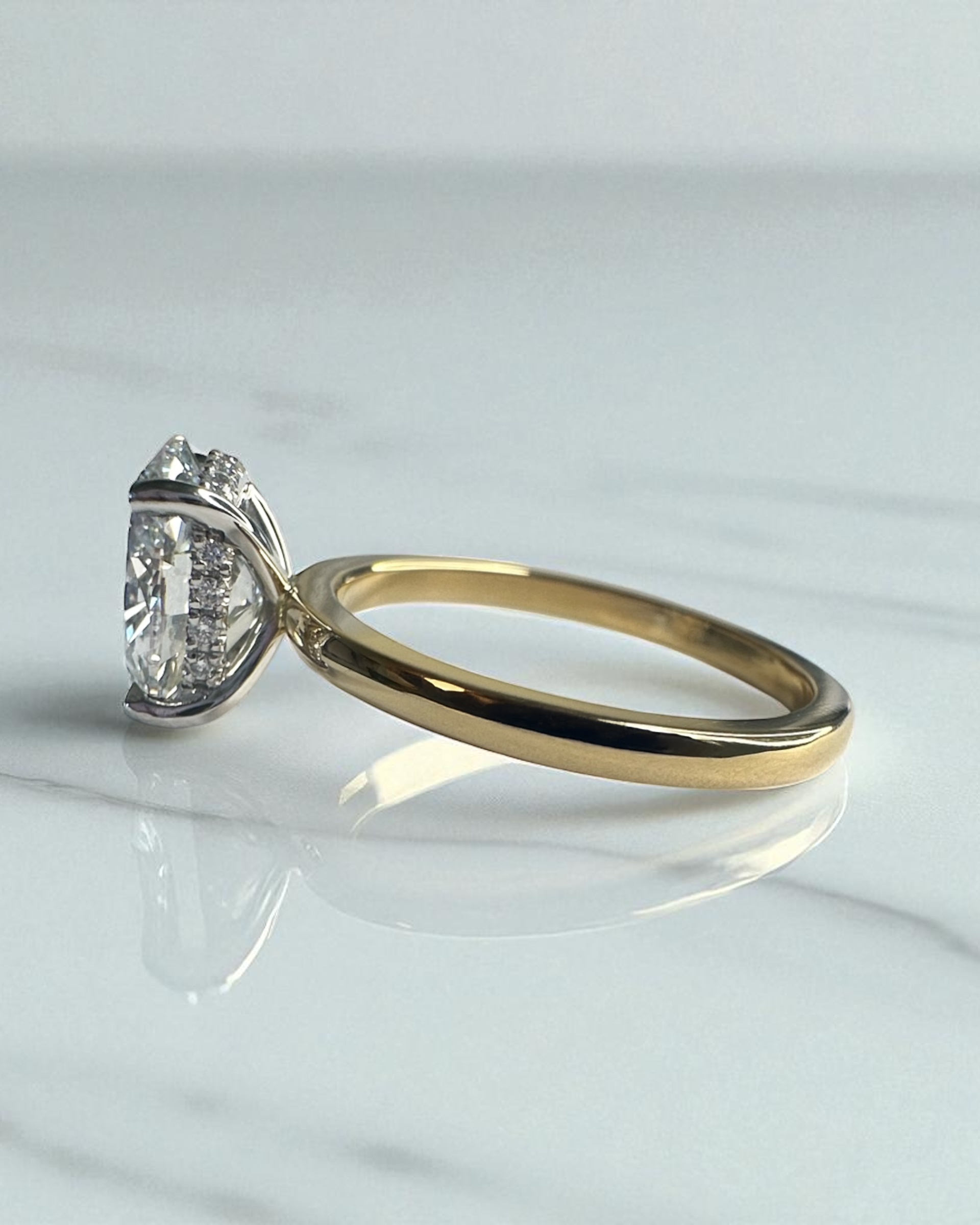2ct lab grown oval cut diamond set in a two tone 18kt yellow gold plain band solitaire, hidden halo engagement ring