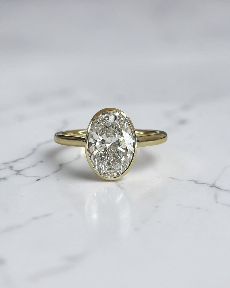 2ct oval cut lab grown diamond bezel set engagement ring in yellow gold with polished solitaire band