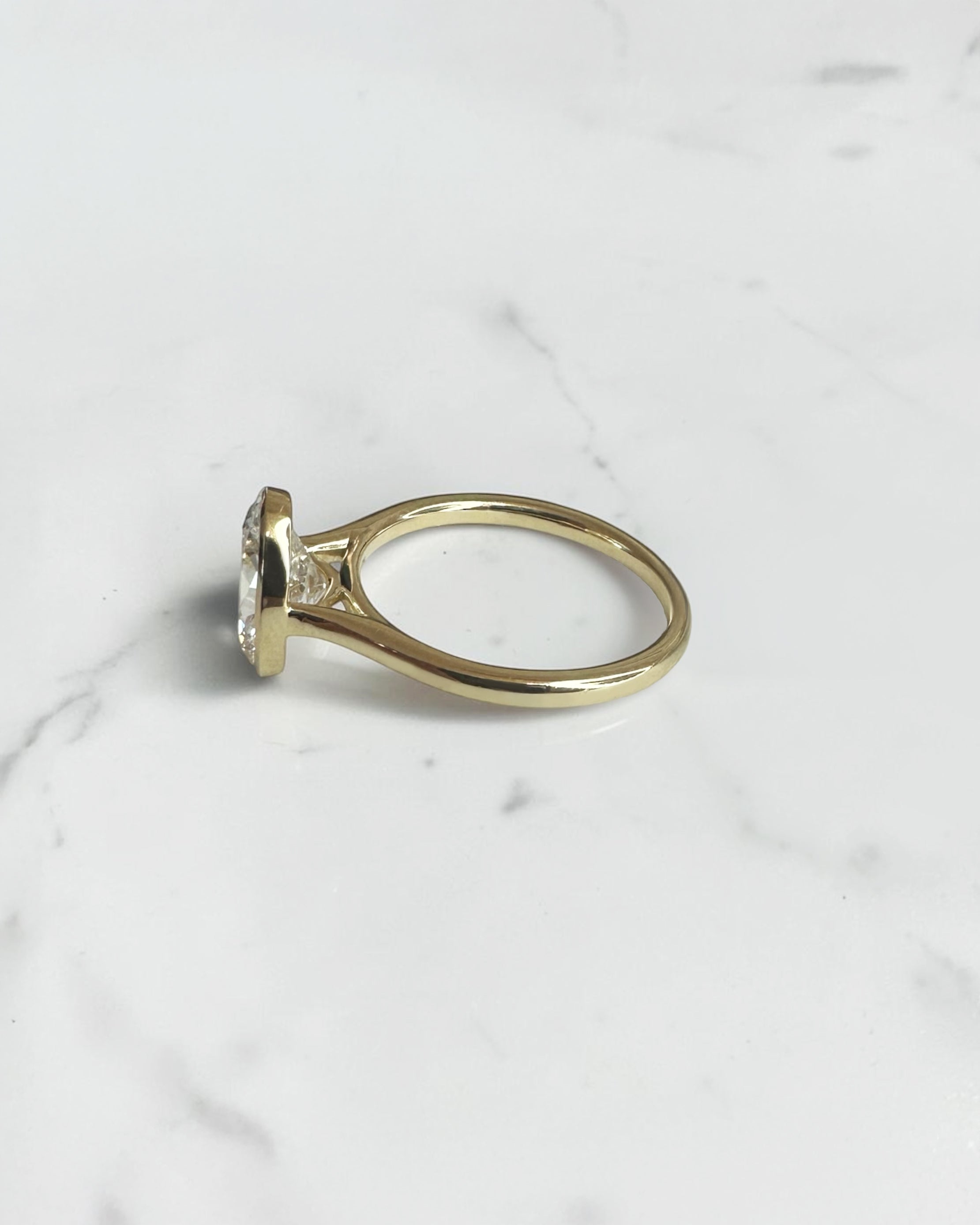 2ct oval cut lab grown diamond bezel set engagement ring in yellow gold with polished solitaire band