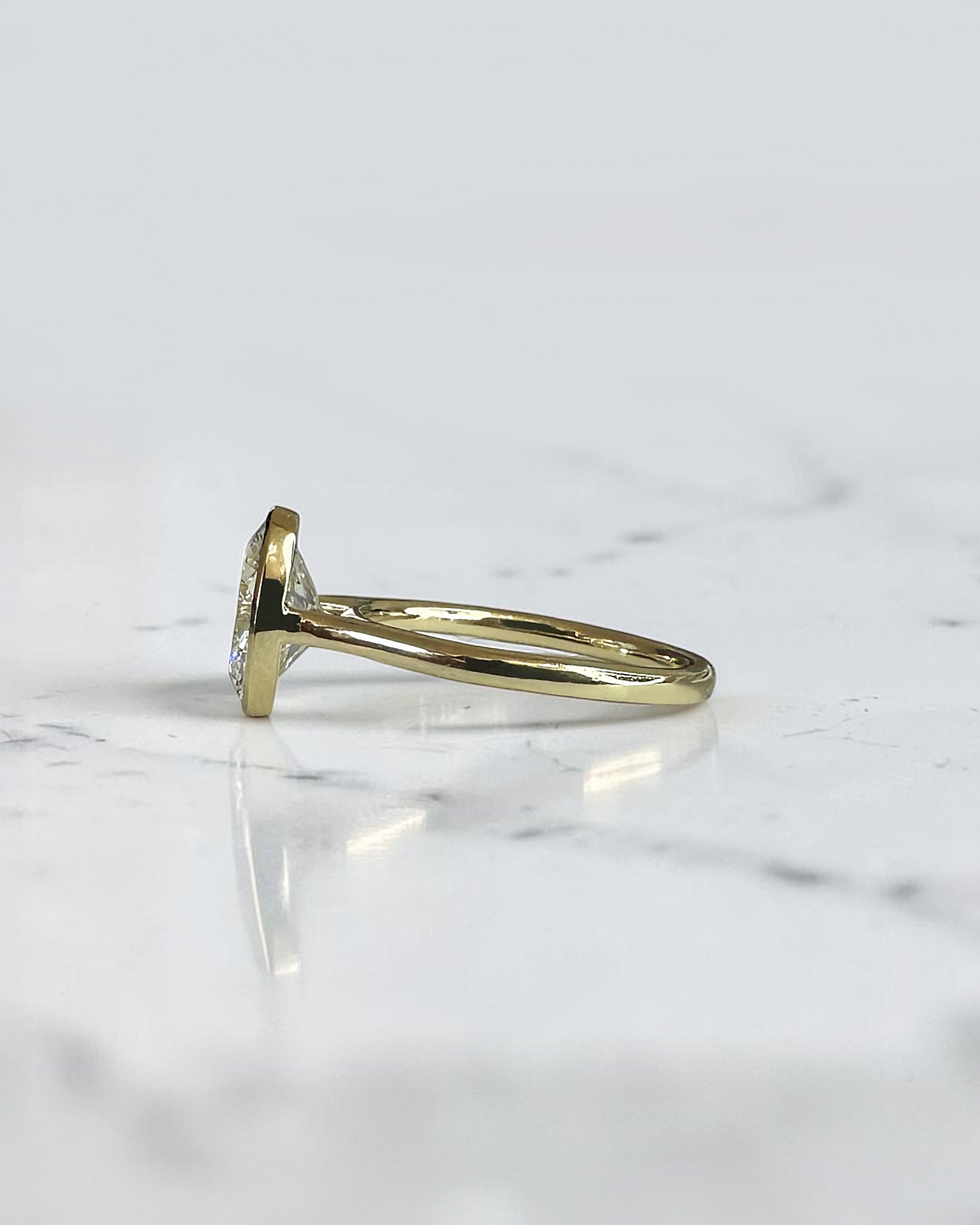2ct oval cut lab grown diamond bezel set engagement ring in yellow gold with polished solitaire band