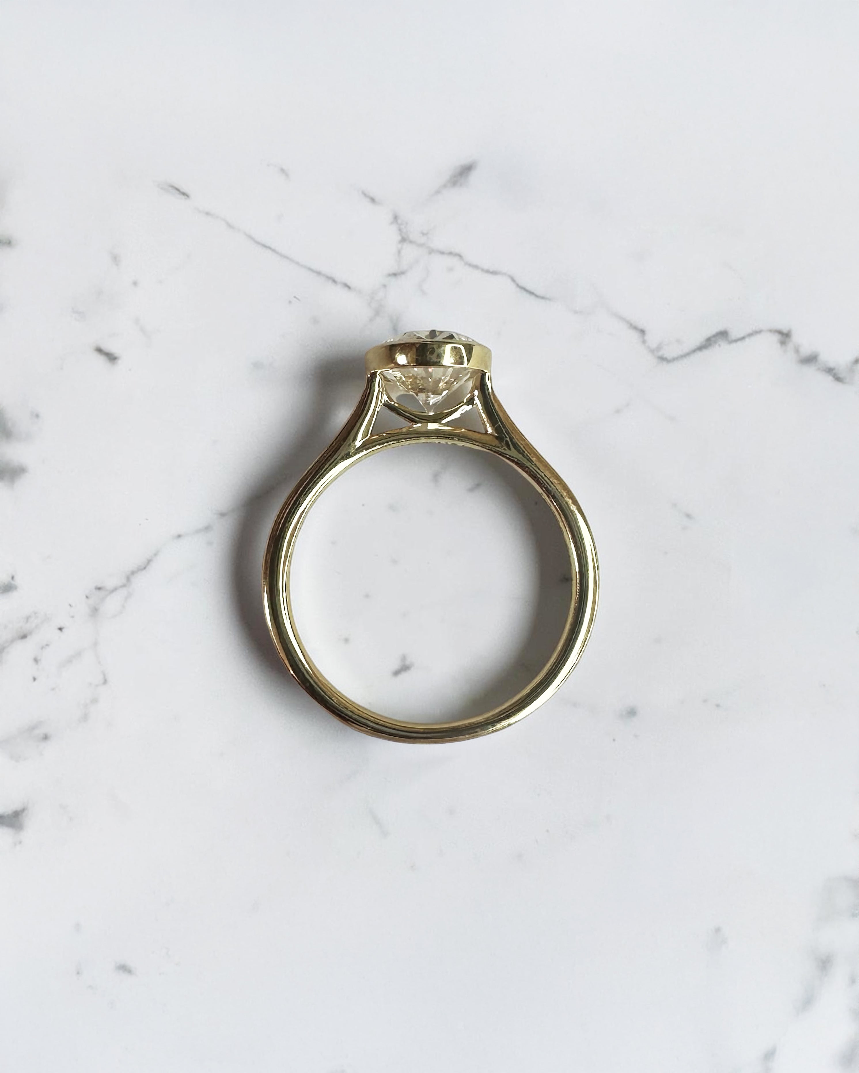 2ct oval cut lab grown diamond bezel set engagement ring in yellow gold with polished solitaire band