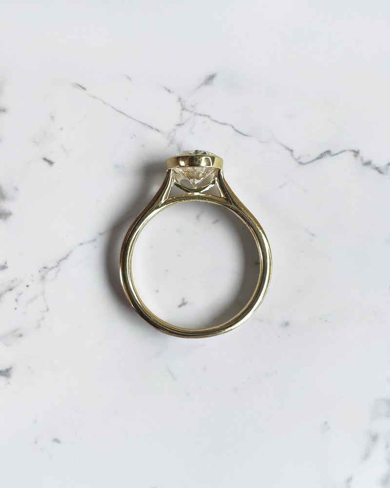 2ct oval cut lab grown diamond bezel set engagement ring in yellow gold with polished solitaire band