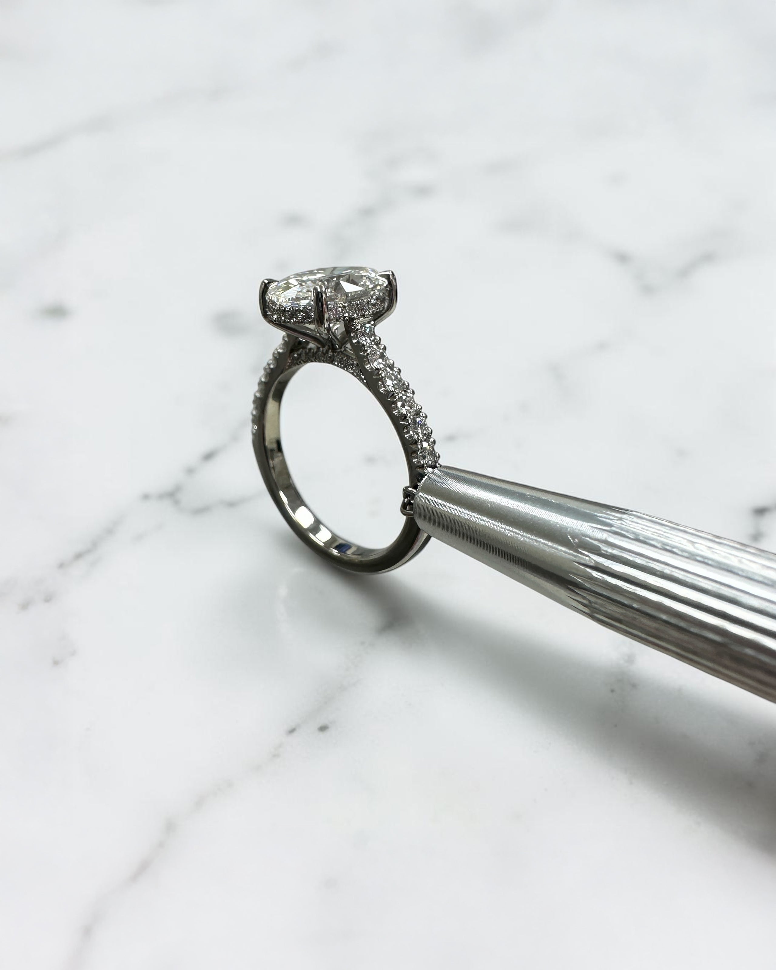 2ct oval cut lab grown diamond cathedral engagement ring with hidden halo, diamond bridge and pavé diamond shoulder band in platinum
