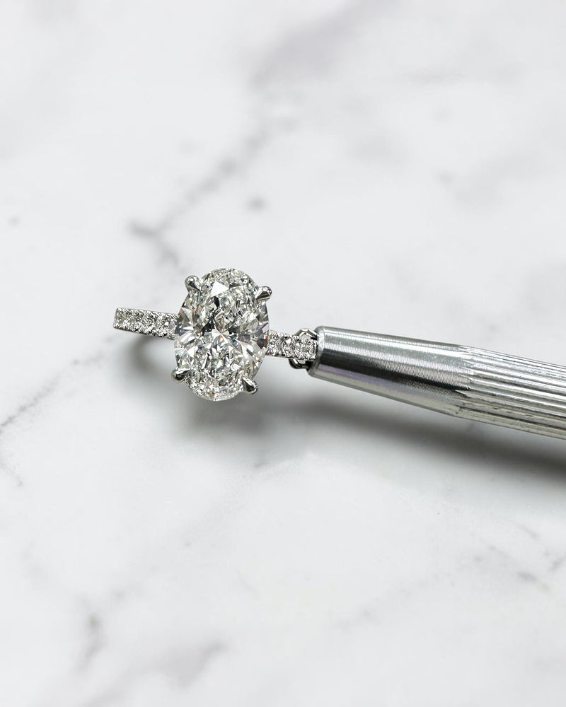 2ct oval cut lab grown diamond cathedral engagement ring with hidden halo, diamond bridge and pavé diamond shoulder band in platinum
