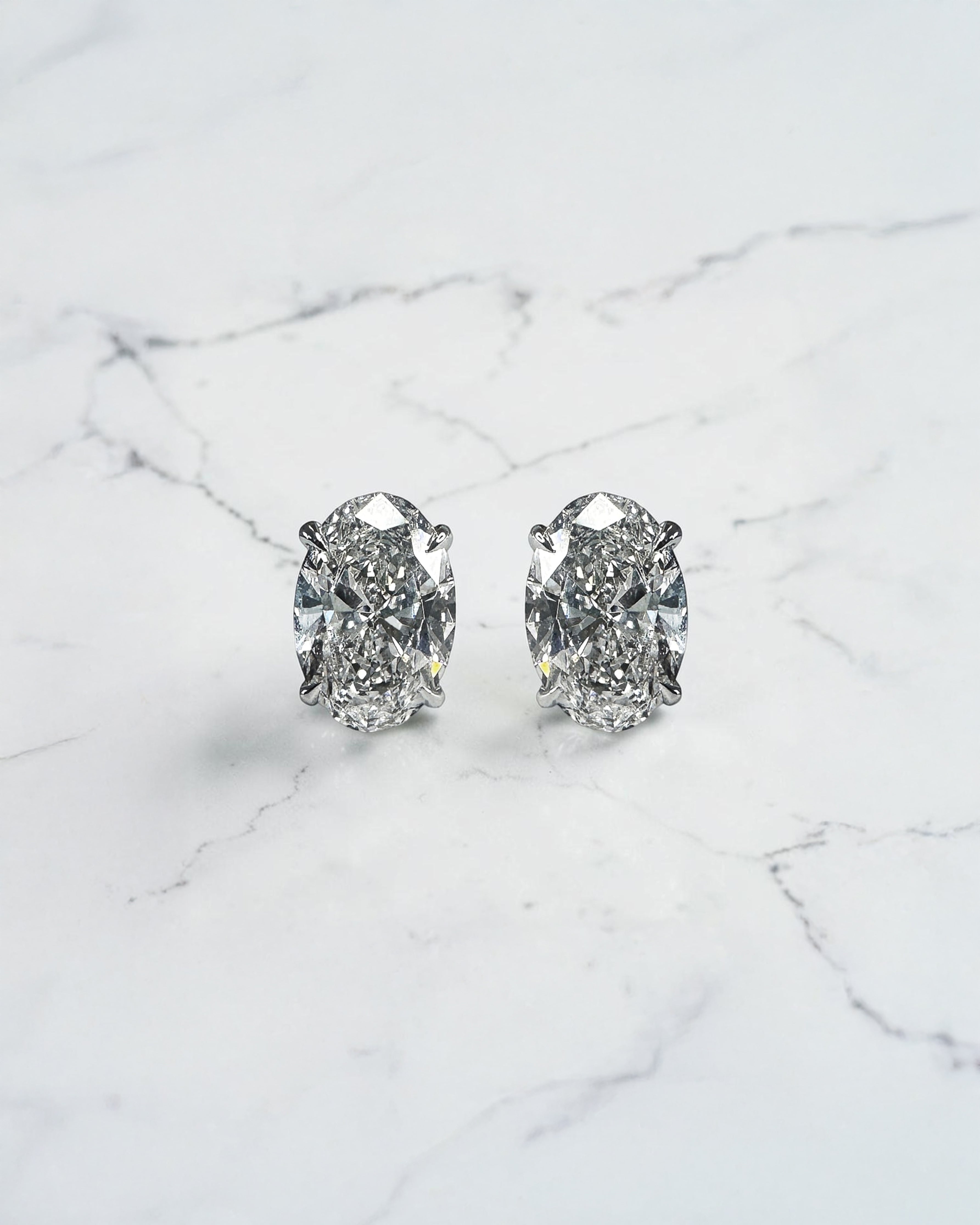 2ct lab grown oval diamond stud earrings featuring two 1ct oval brilliant cut diamonds in a classic four prong setting.