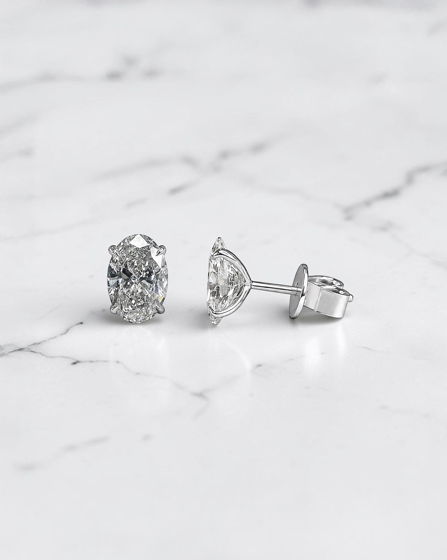 2ct lab grown oval diamond stud earrings featuring two 1ct oval brilliant cut diamonds in a classic four prong setting.