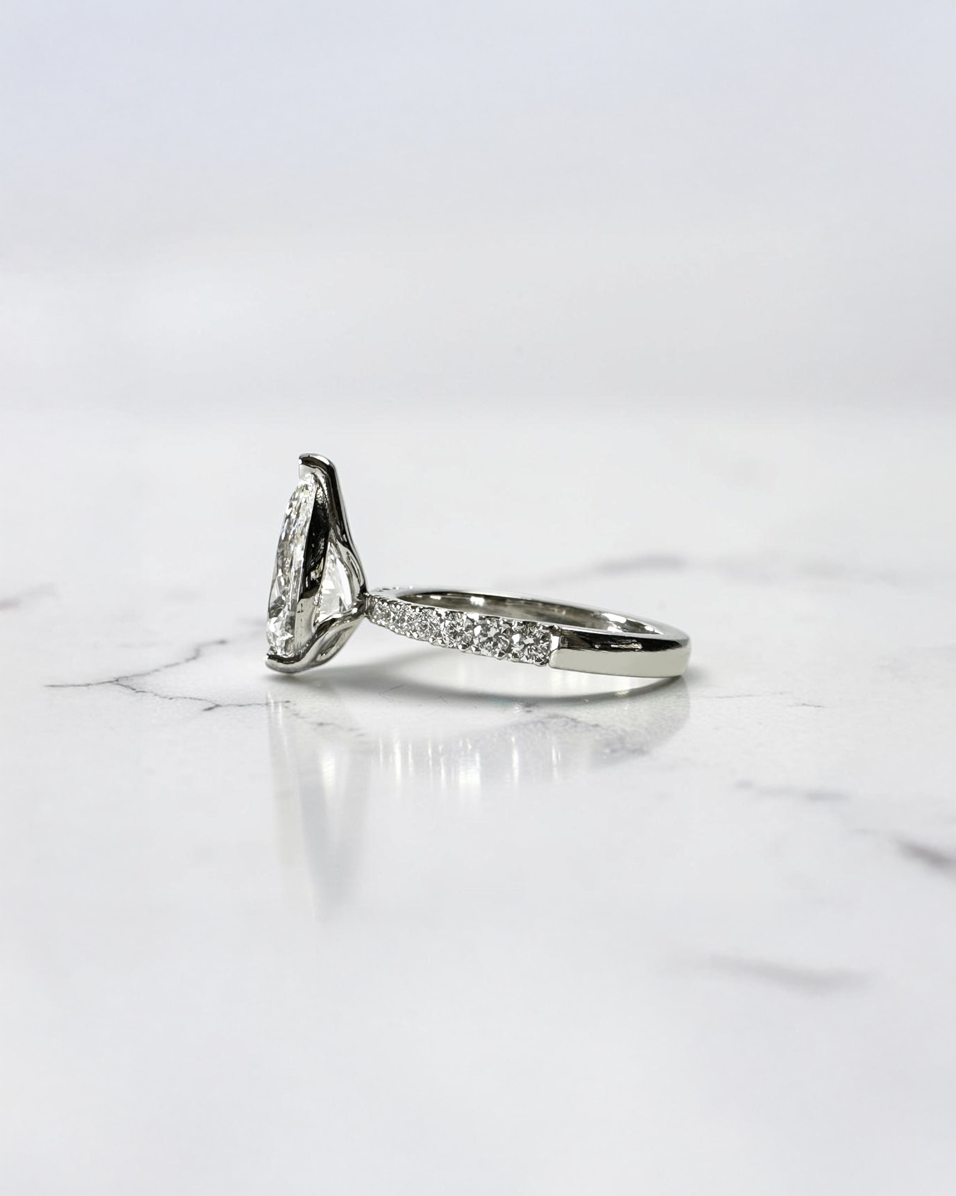 2ct pear cut lab grown diamond engagement ring with tapered diamond shoulder band and lotus three prong setting in platinum, handmade in London.