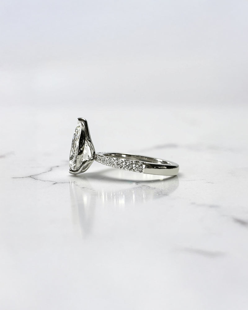 2ct pear cut lab grown diamond engagement ring with tapered diamond shoulder band and lotus three prong setting in platinum, handmade in London.