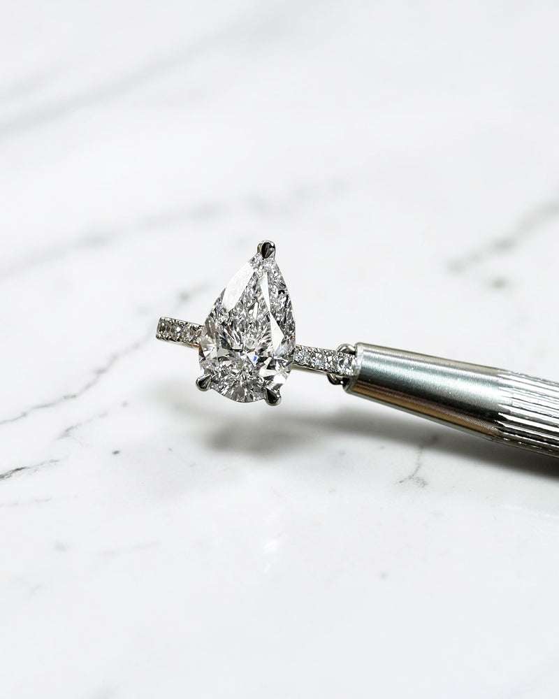 2ct pear cut lab grown diamond engagement ring with tapered diamond shoulder band and lotus three prong setting in platinum, handmade in London.