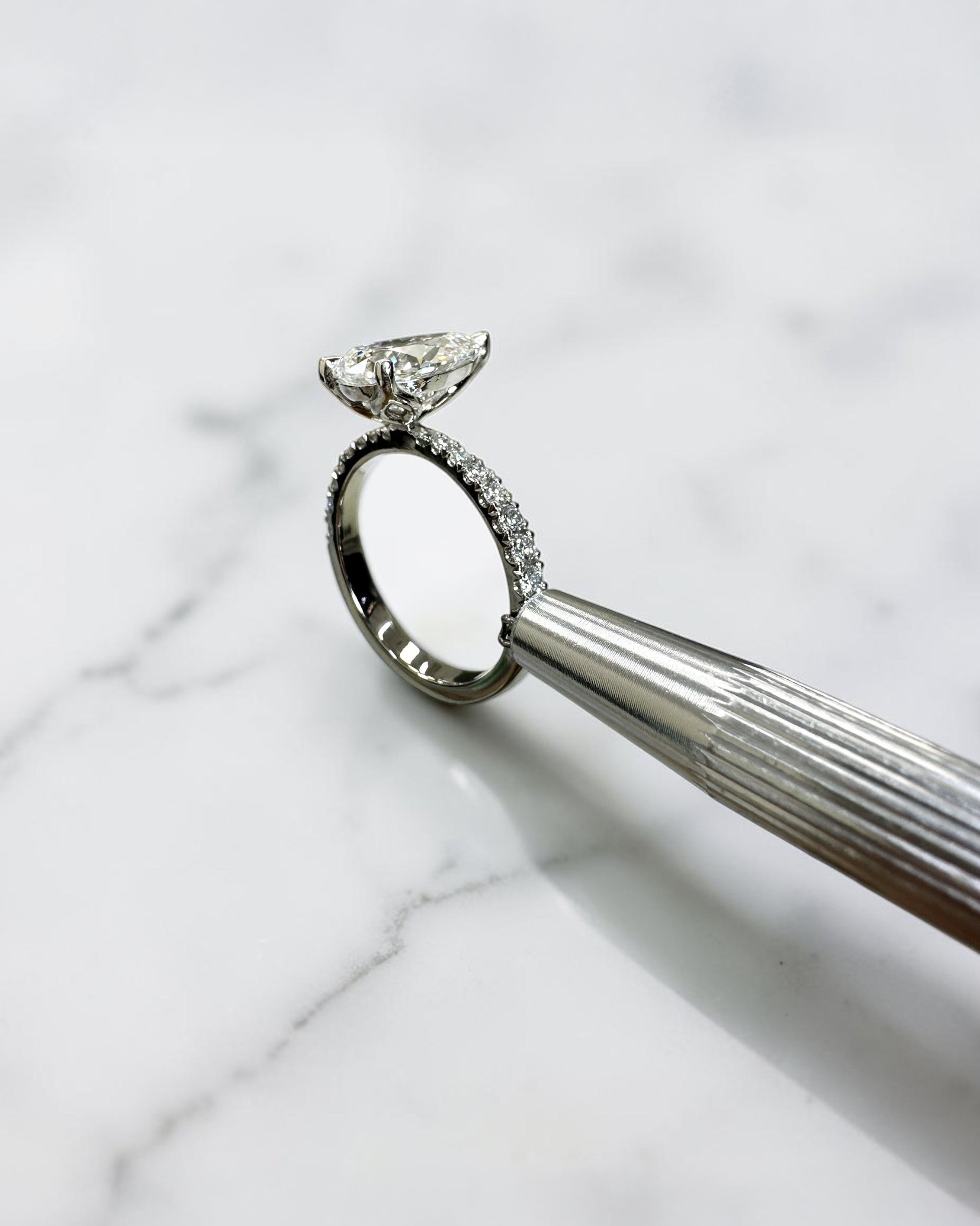 2ct pear cut lab grown diamond engagement ring with tapered diamond shoulder band and lotus three prong setting in platinum, handmade in London.