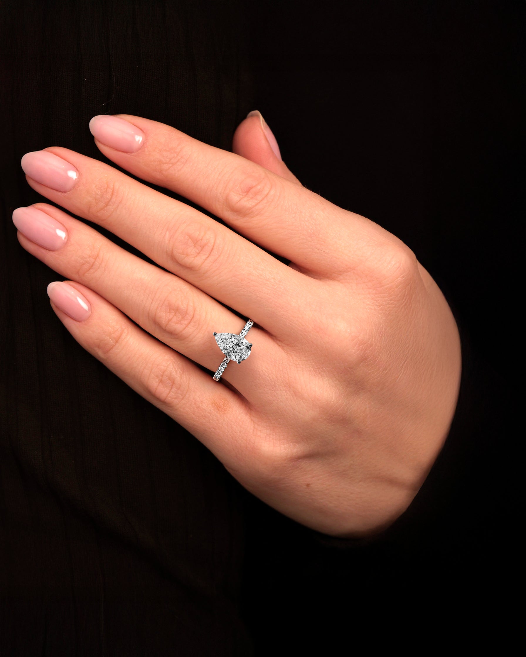 2ct pear cut lab grown diamond engagement ring on hand with cathedral setting, diamond shoulder band, hidden halo and diamond bridge, handcrafted in platinum by Layla Diamonds.