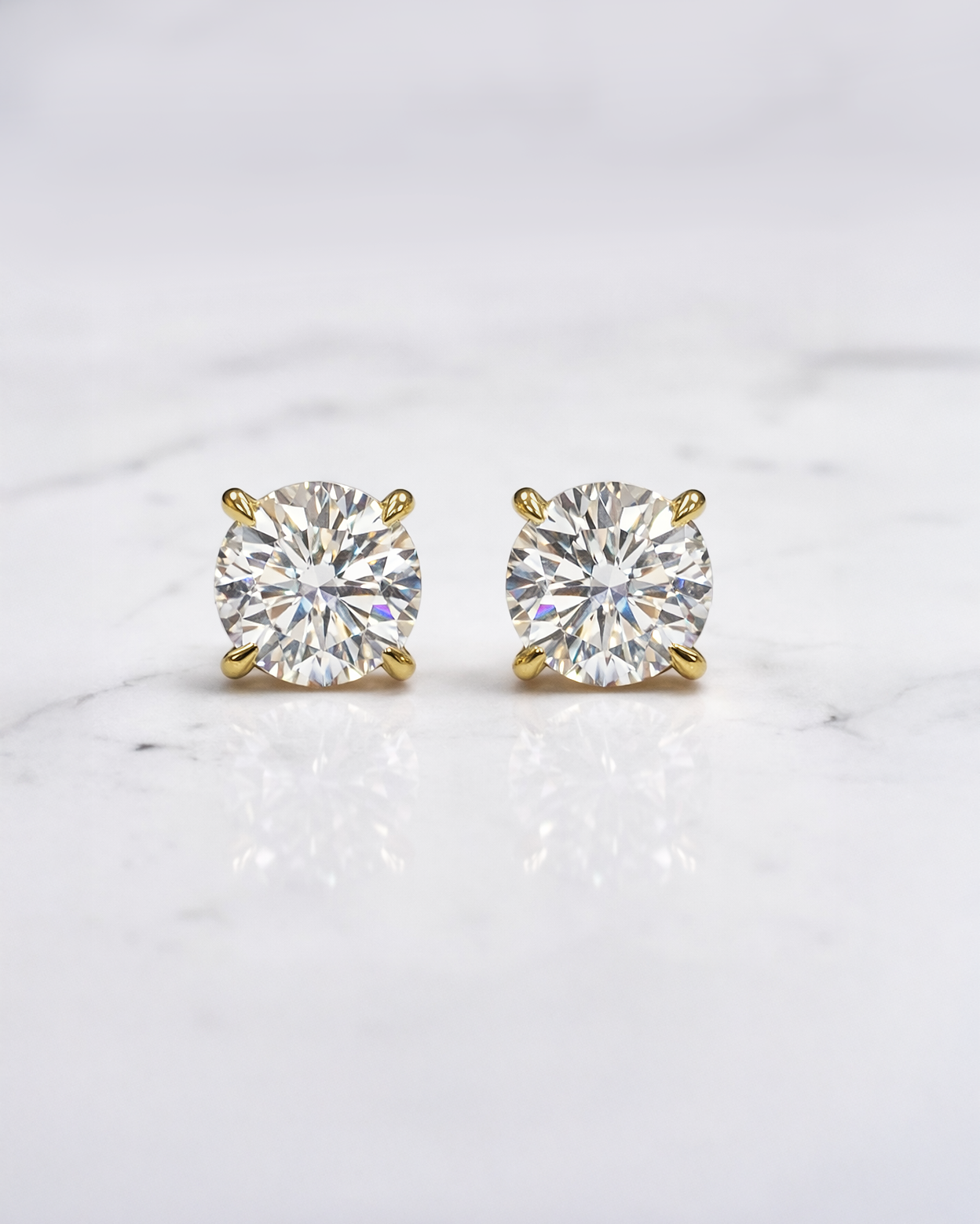 2ct total lab grown diamond stud earrings in martini setting on ear, round brilliant diamonds in yellow gold. Made in London