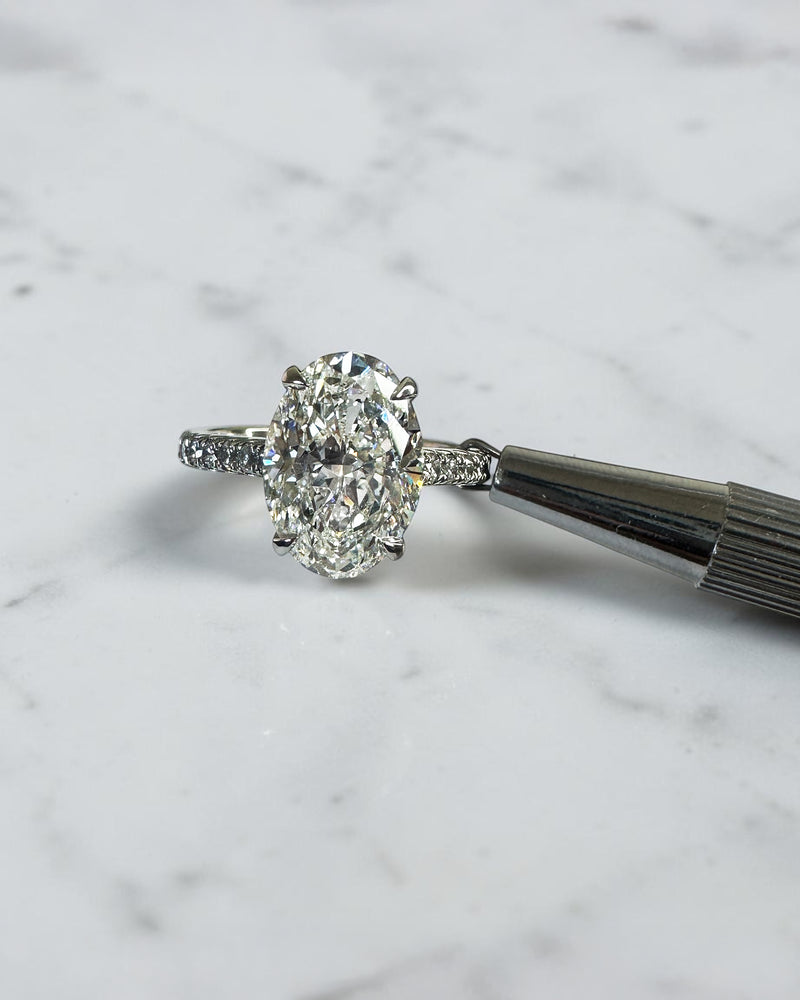 3.50ct oval cut lab grown diamond cathedral hidden halo engagement ring with diamond set shoulders and diamond bridge in platinum
