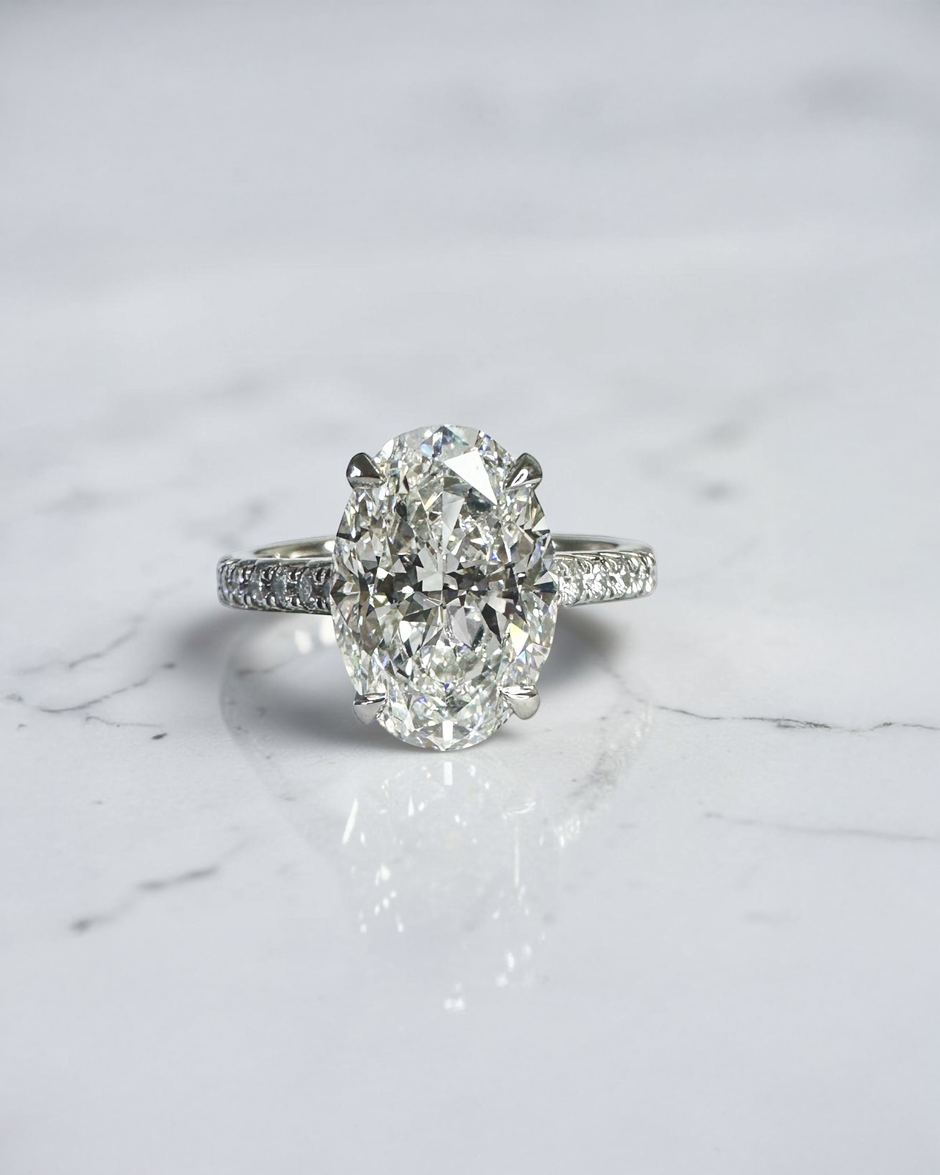 3.50ct oval cut lab grown diamond cathedral hidden halo engagement ring with diamond set shoulders and diamond bridge in platinum
