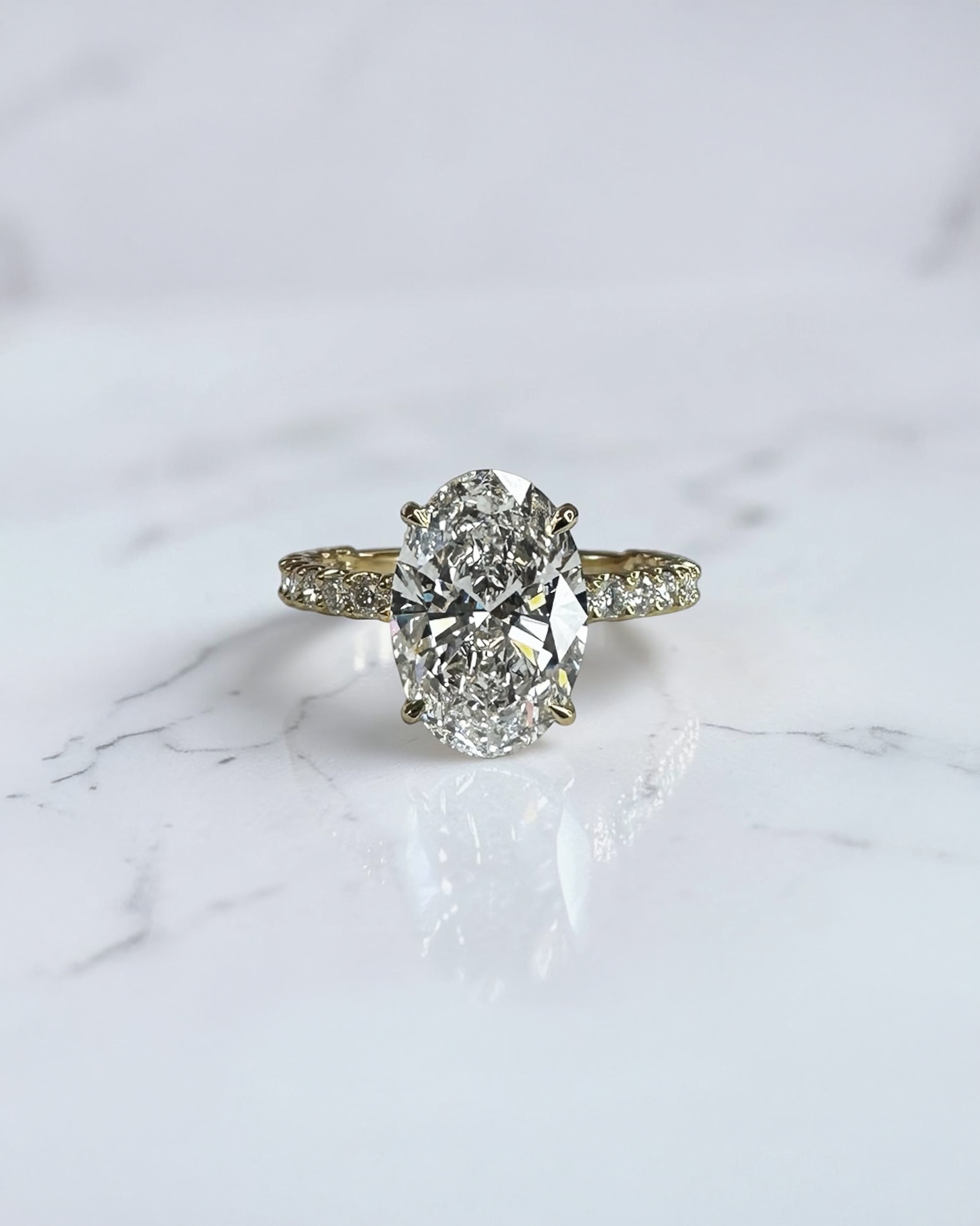 3.50ct oval cut lab grown diamond engagement ring with U prong floating setting and diamond set shoulders in yellow gold
