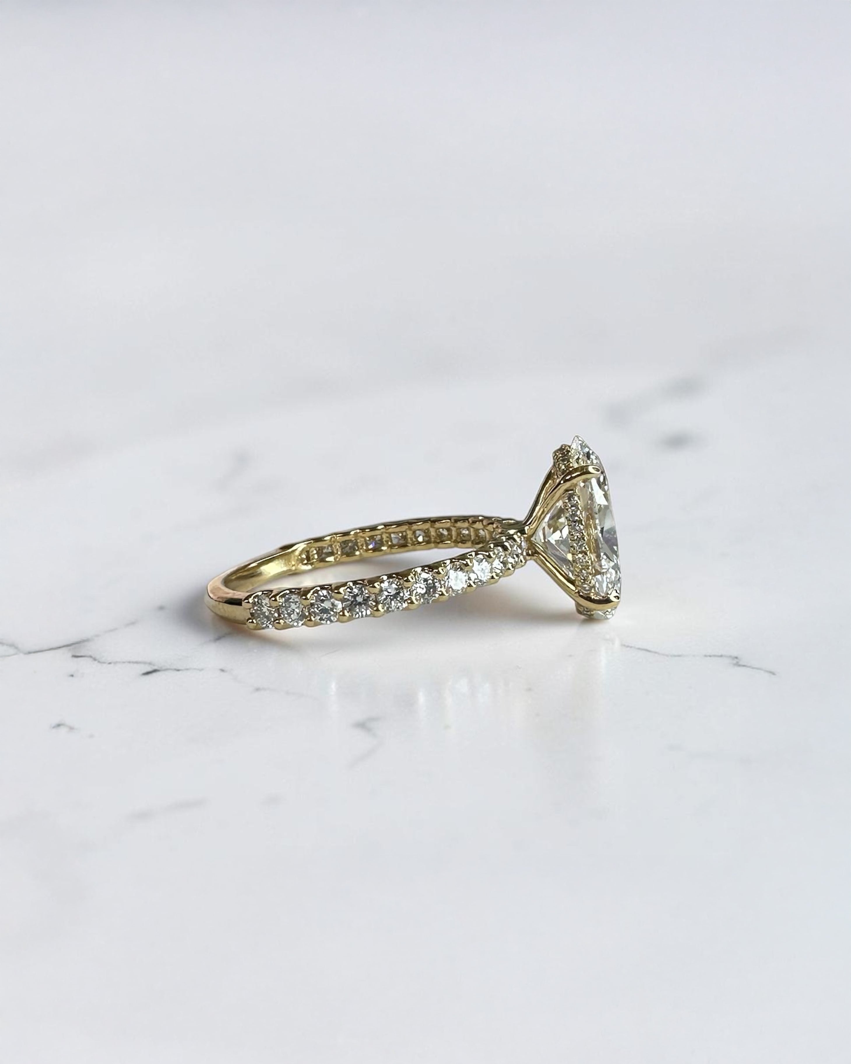 3.50ct oval cut lab grown diamond engagement ring with U prong floating setting and diamond set shoulders in yellow gold
