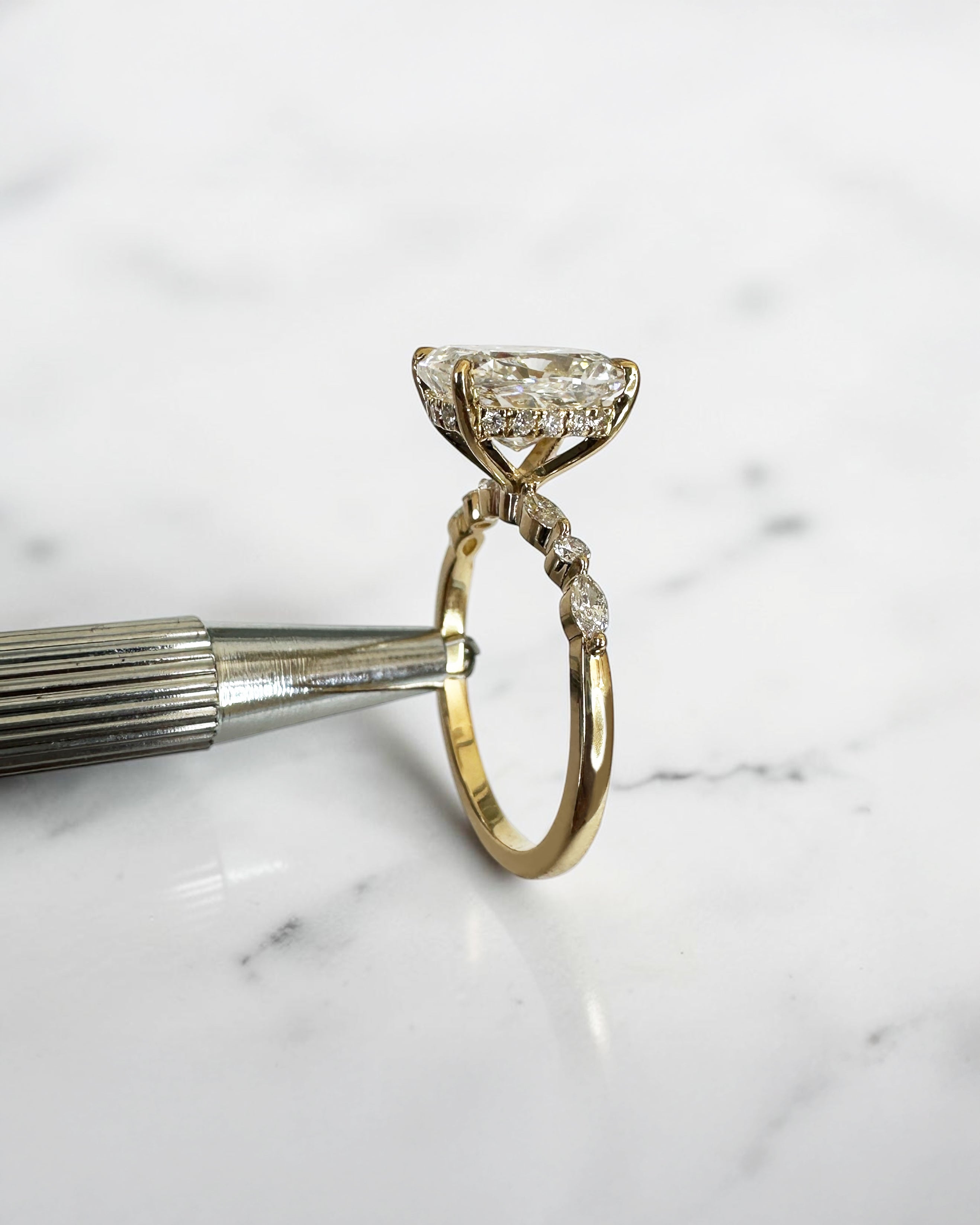 3ct elongated cushion cut lab grown diamond engagement ring with hidden halo, floating head setting and marquise and round diamond band in yellow gold, handmade in London.
