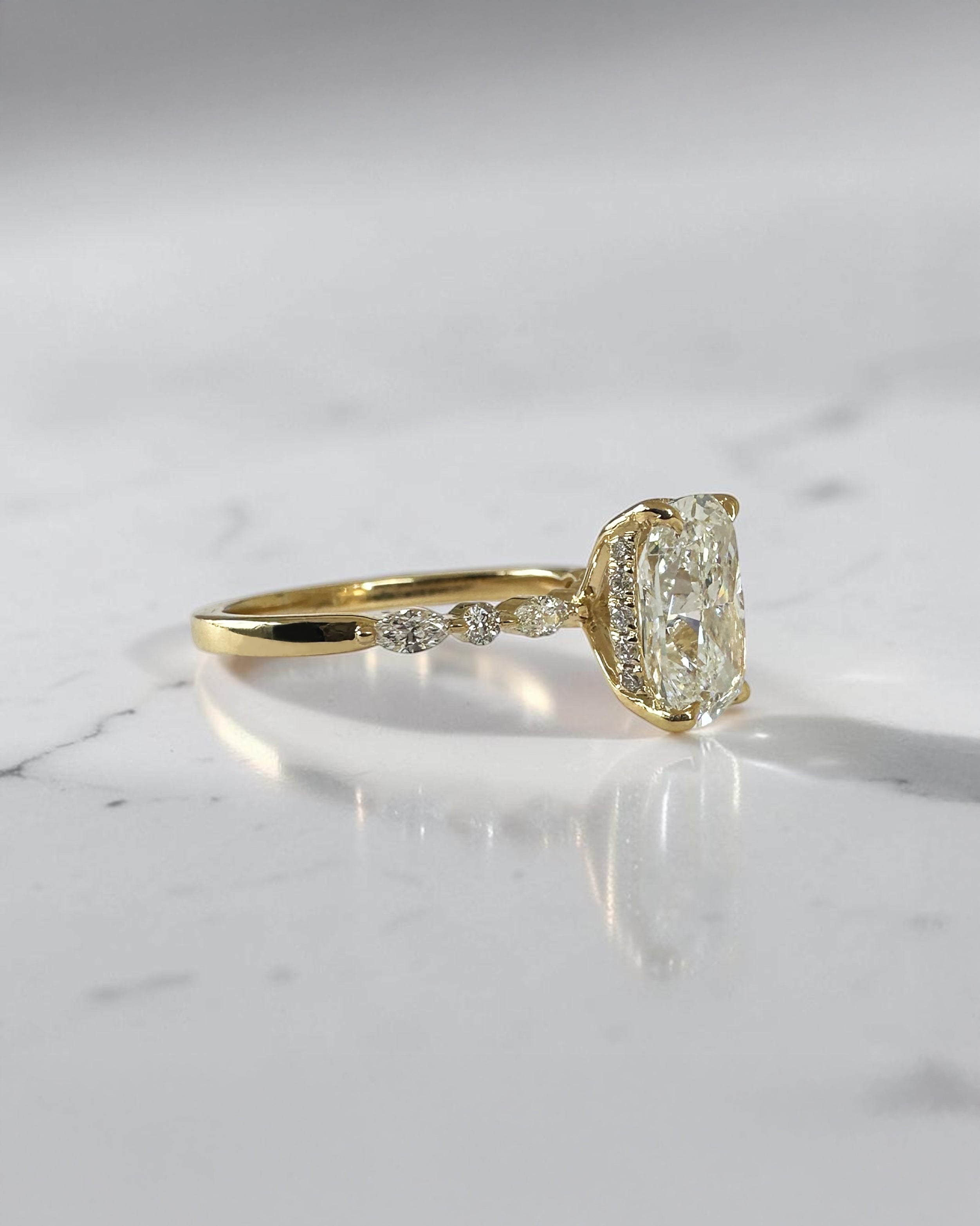 3ct elongated cushion cut lab grown diamond engagement ring featuring a hidden halo, floating head setting and marquise diamond band in 18kt yellow gold.