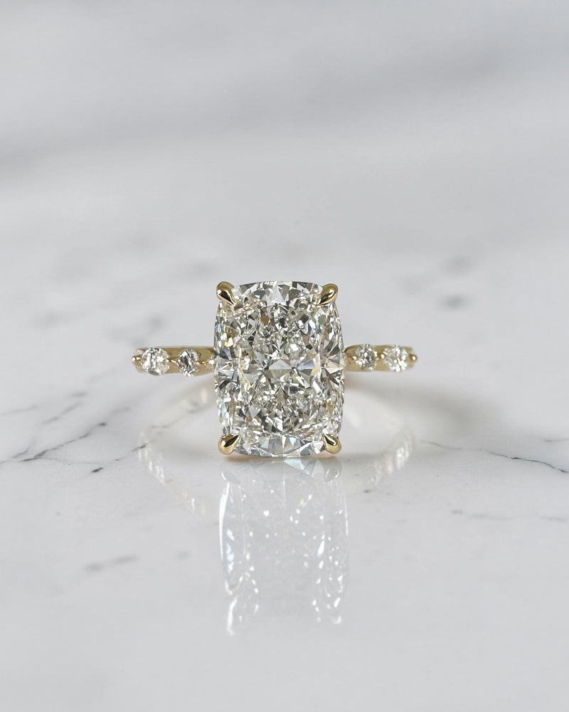 3ct elongated cushion cut lab grown diamond engagement ring featuring a hidden halo, floating head setting and marquise diamond band in 18kt yellow gold.
