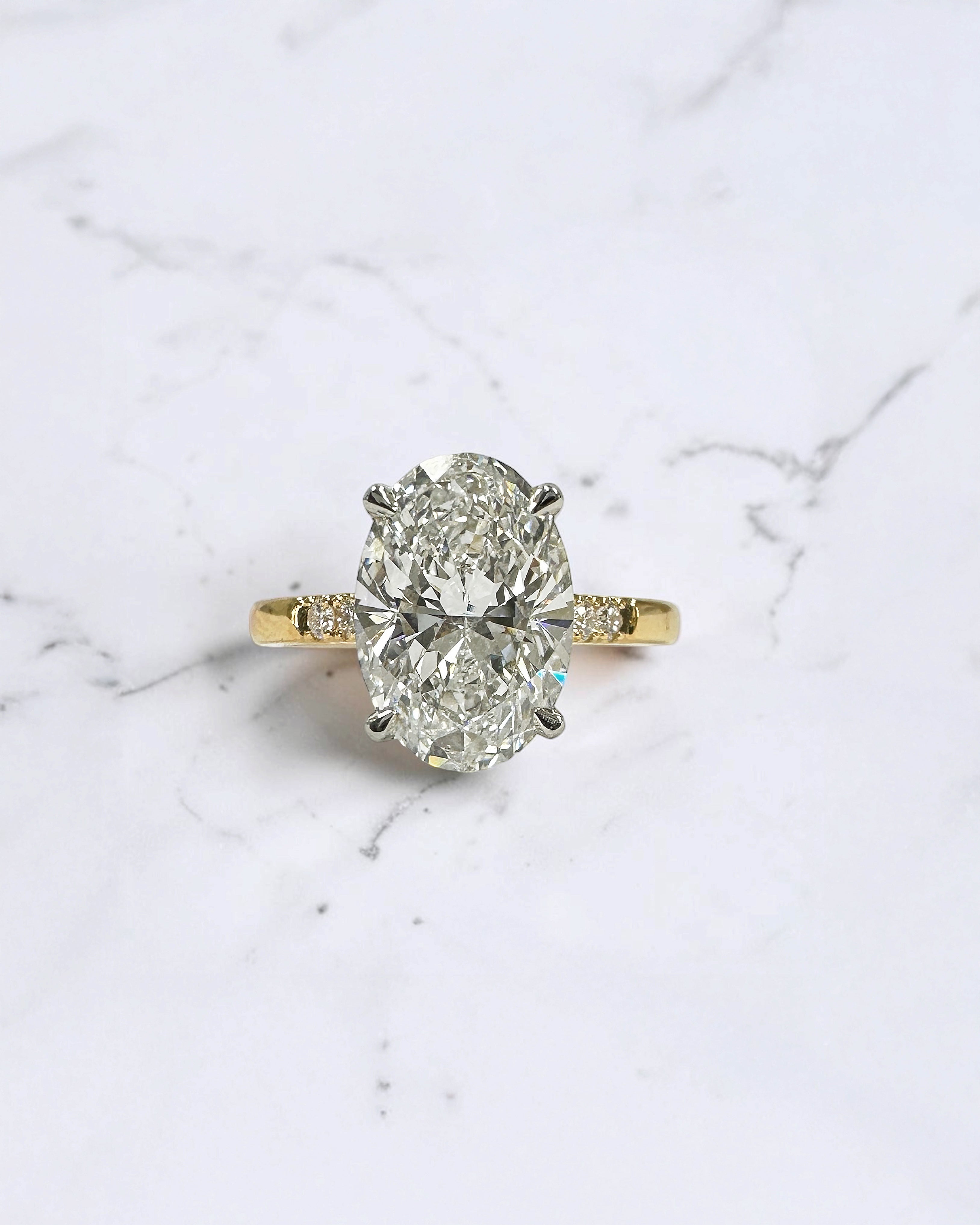 3ct oval cut lab grown diamond engagement ring with a cathedral setting, partial pavé diamond band and diamond wrap around hidden halo. Handmade in London and available in platinum or 18kt yellow gold.
