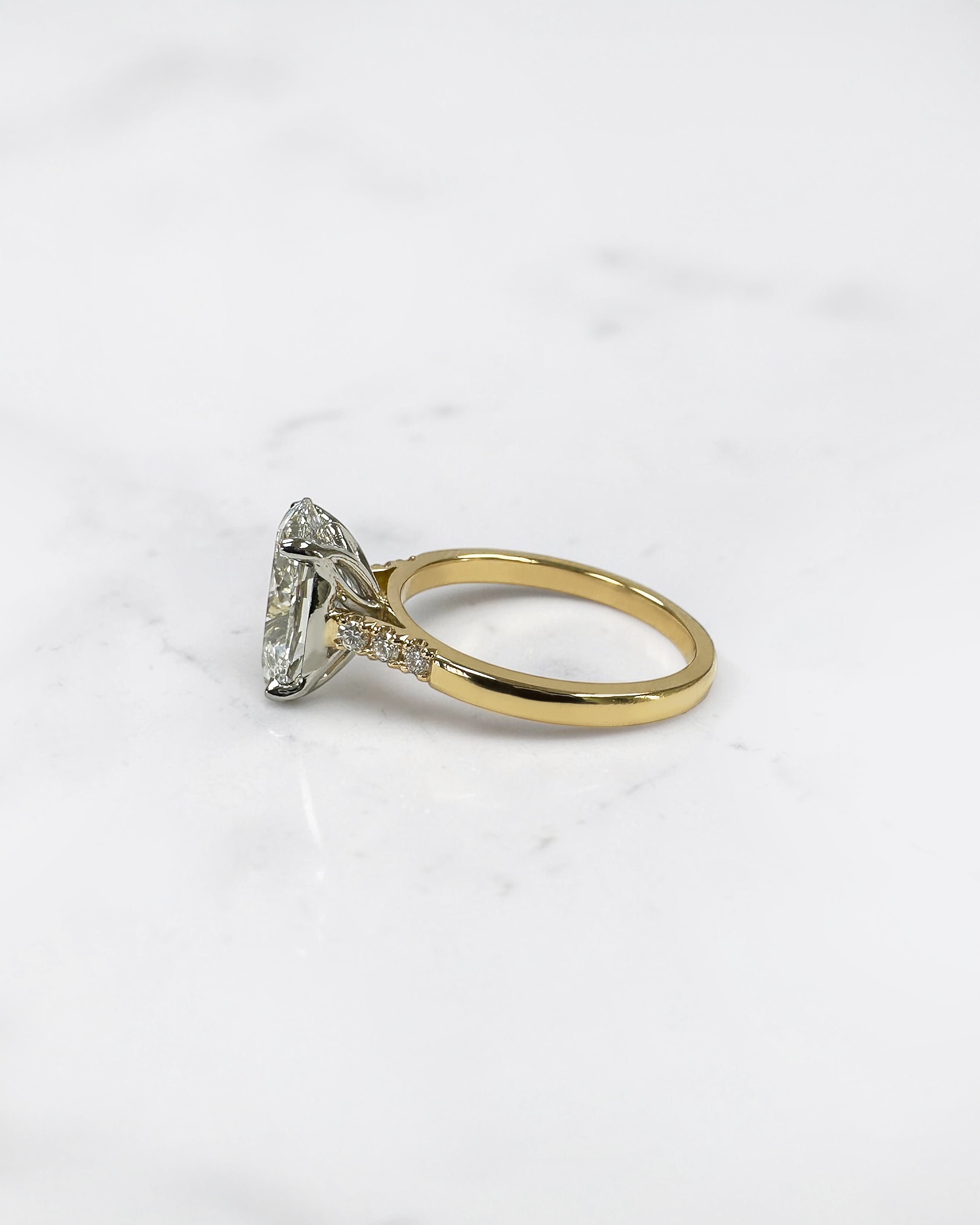 3ct oval cut lab grown diamond engagement ring with a cathedral setting, partial pavé diamond band and diamond wrap around hidden halo. Handmade in London and available in platinum or 18kt yellow gold.
