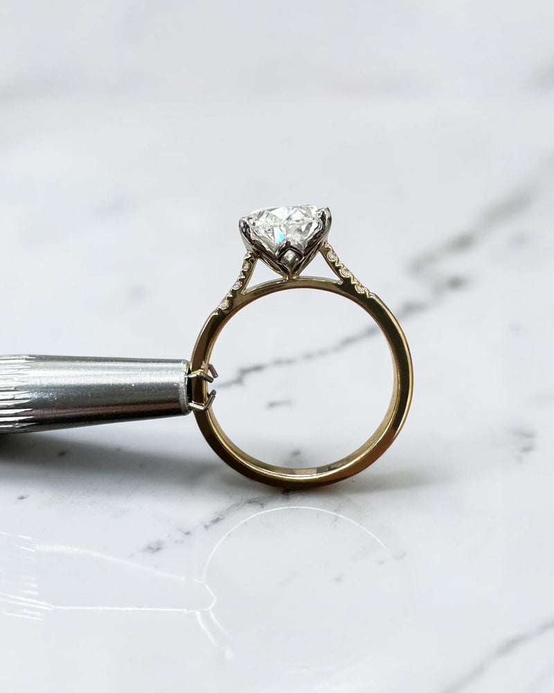 3ct oval cut lab grown diamond engagement ring with a cathedral setting, partial pavé diamond band and diamond wrap around hidden halo. Handmade in London and available in platinum or 18kt yellow gold.

