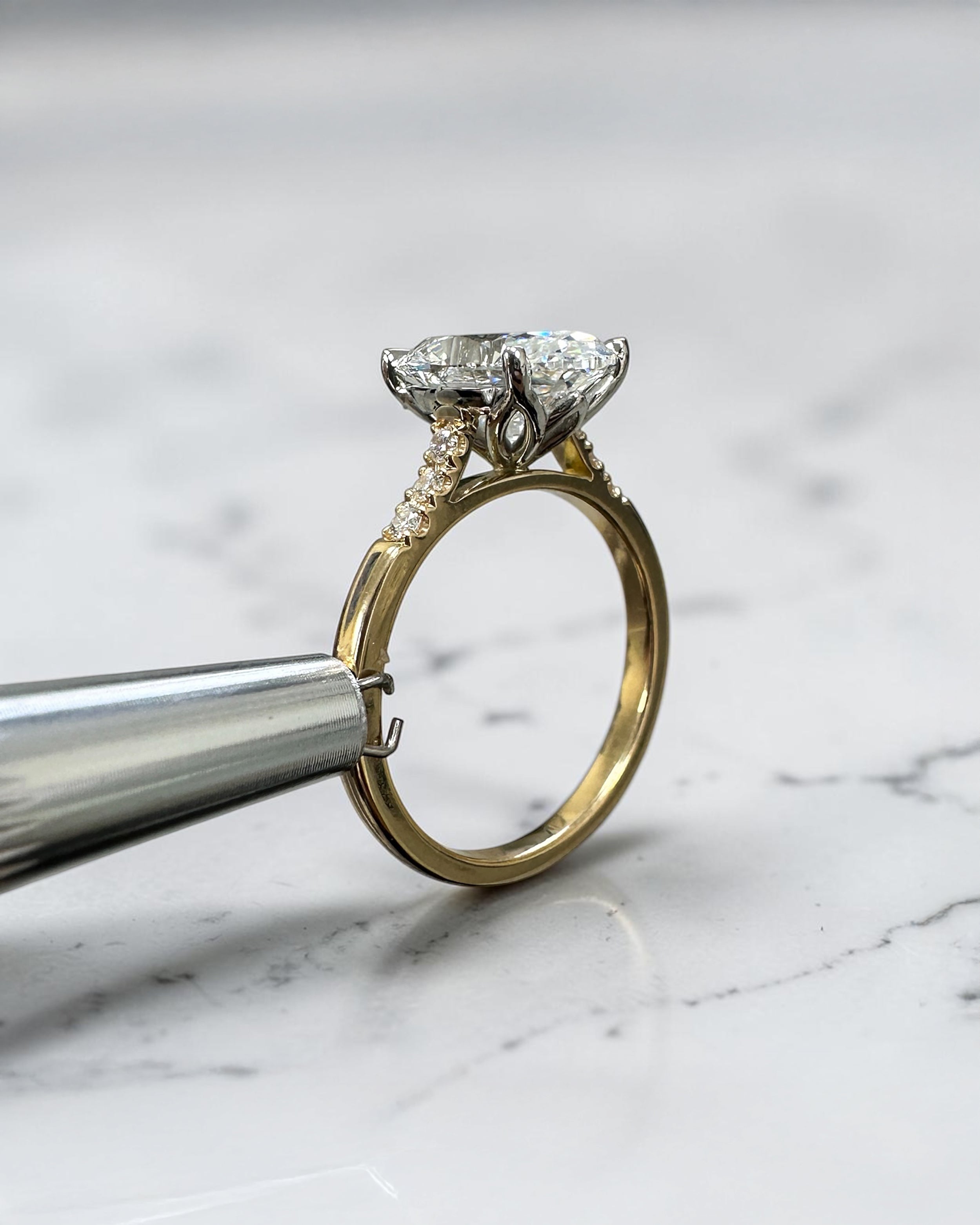 3ct oval cut lab grown diamond engagement ring with a cathedral setting, partial pavé diamond band and diamond wrap around hidden halo. Handmade in London and available in platinum or 18kt yellow gold.
